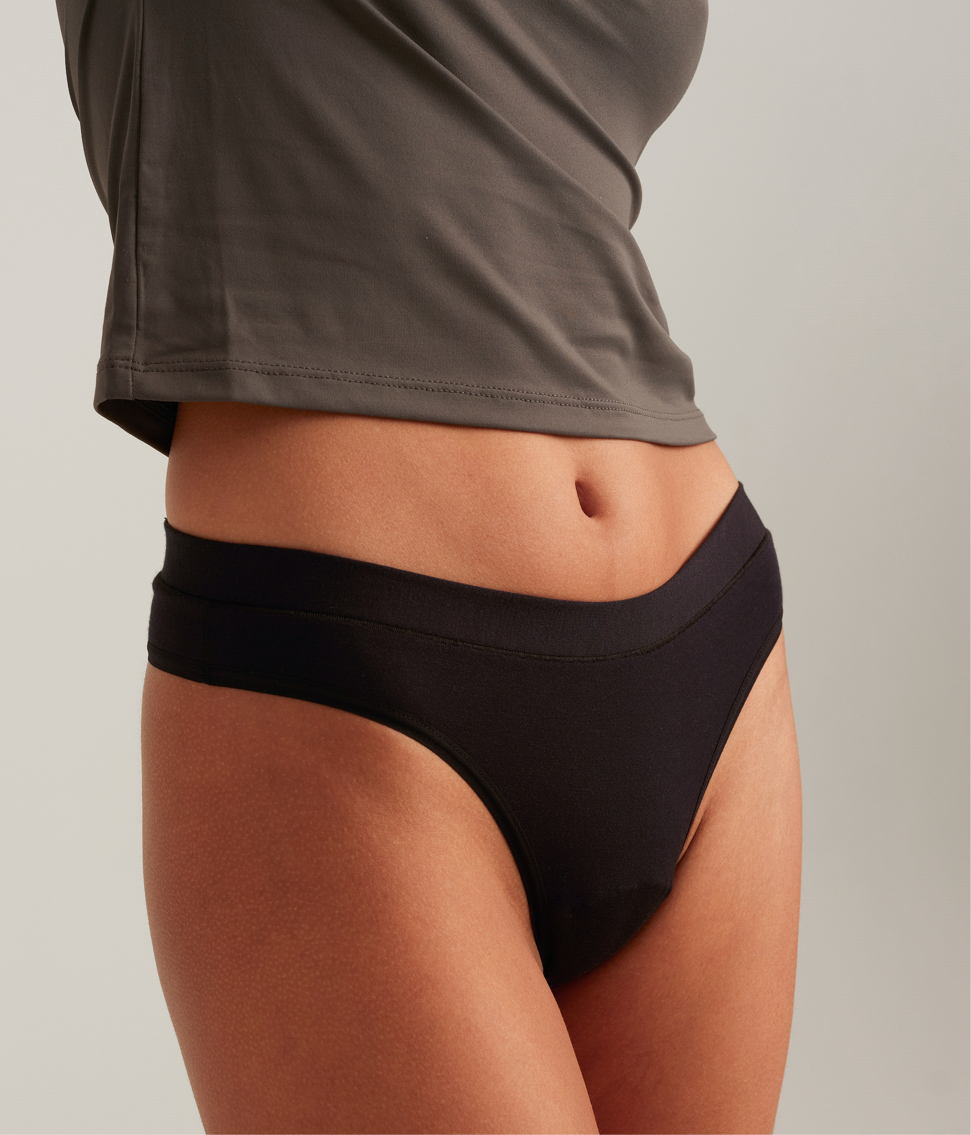 Person wearing black underwear with a neutral background