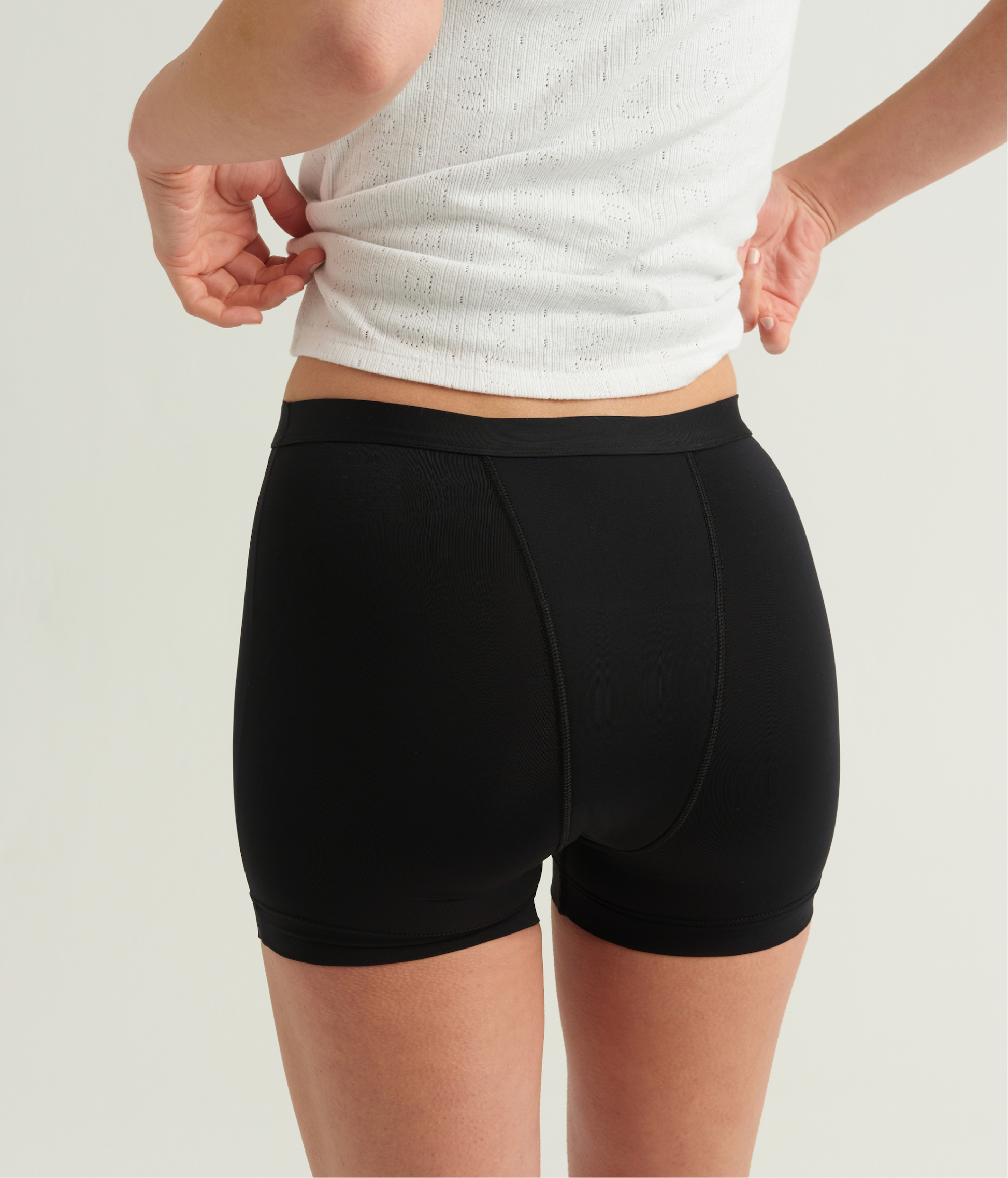 Person wearing black shorts and a white top on a light background