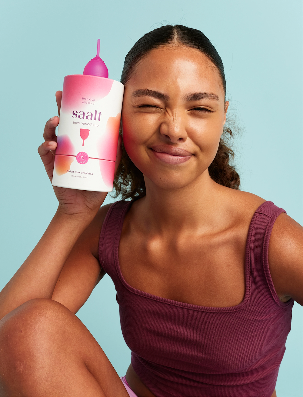 A model holding Saalt’s Teen Menstrual Cup in color Wild Rose. Tone is playful.