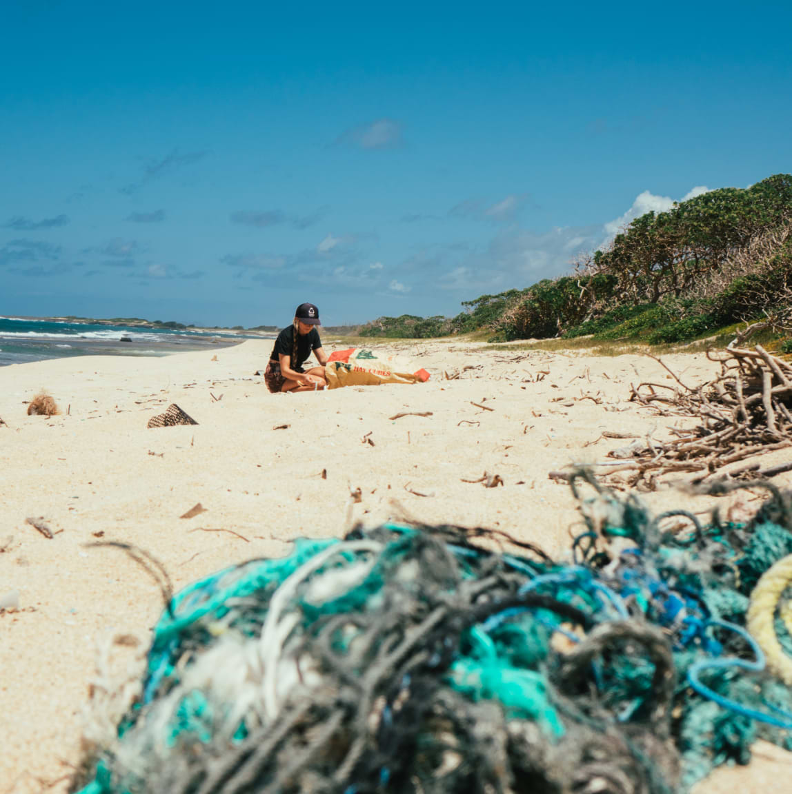 Female picking up trash from the sand in the beach impact banner