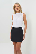 Front view of the black skort with the white stripe on the side paired with a white short-sleeve top.