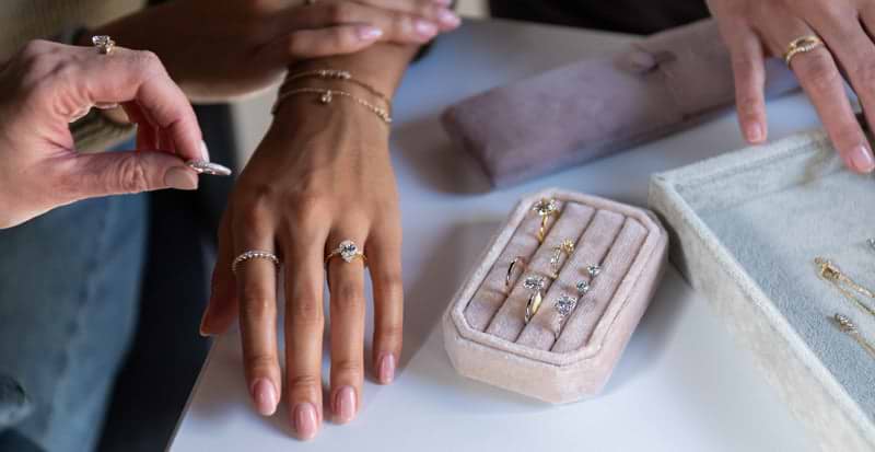 hands choosing white gold and yellow gold rings to try on.