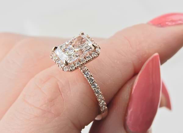 radiant cut diamond with diamond halo engagement ring on a woman's hand