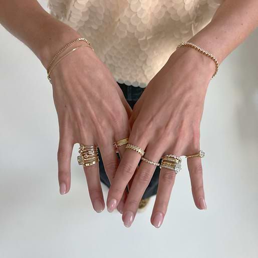 Yellow gold engagement rings and wedding bands stacked on hands.