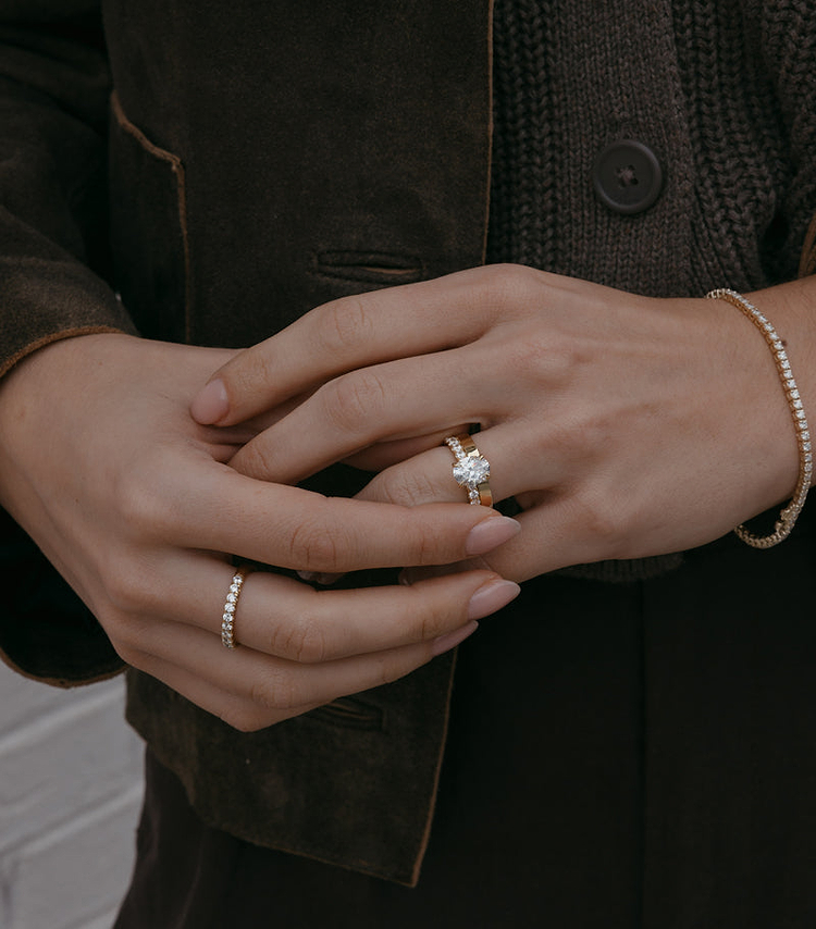 Oval Diamond engagement ring and wide, gold wedding band on hand