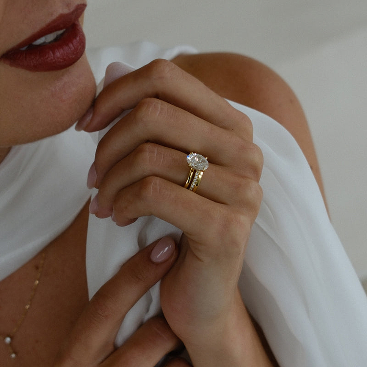 Yellow gold oval engagement ring and wedding band on hand.