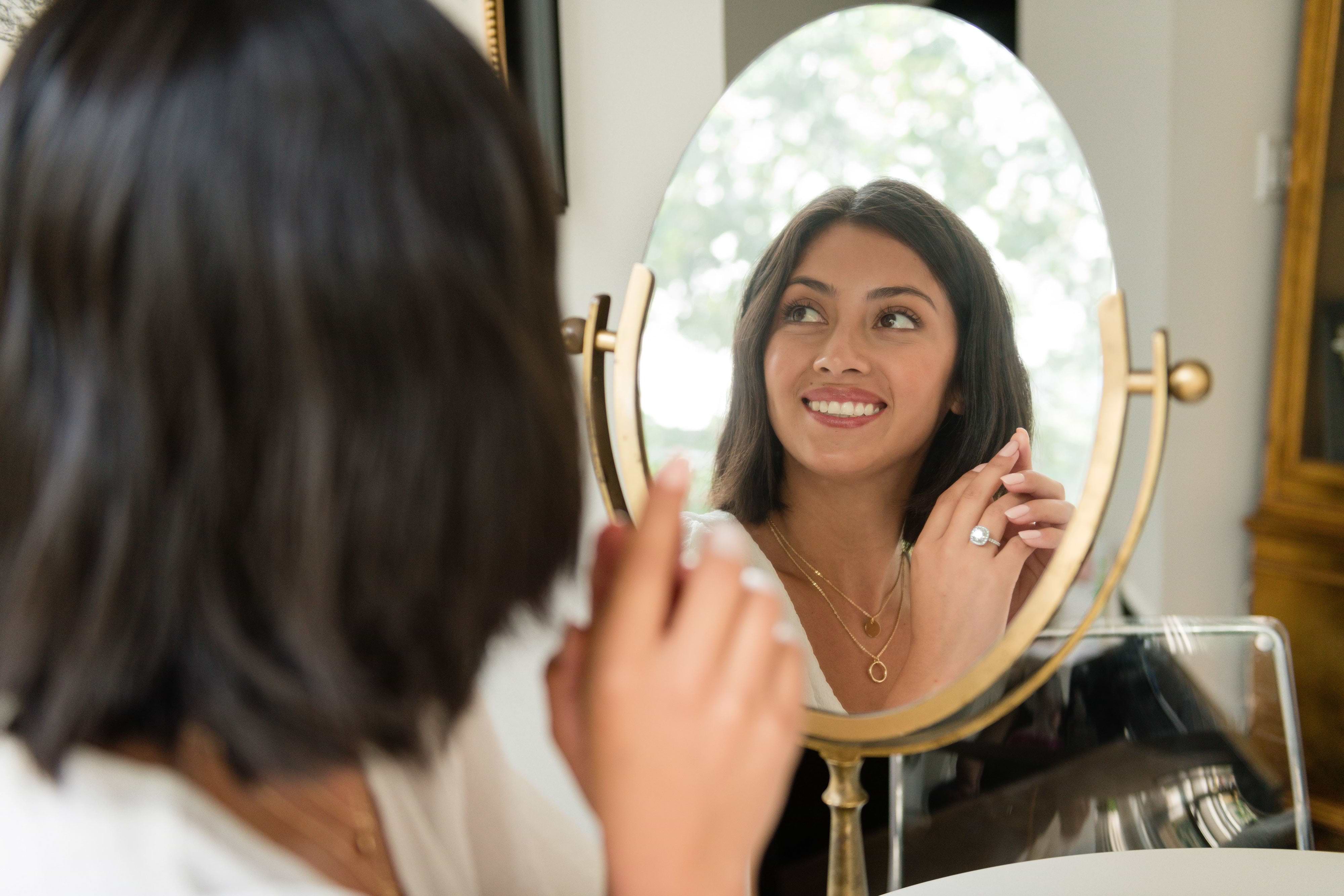 woman sitting in front of a vanity mirror holding up her lab grown diamond engagement ring