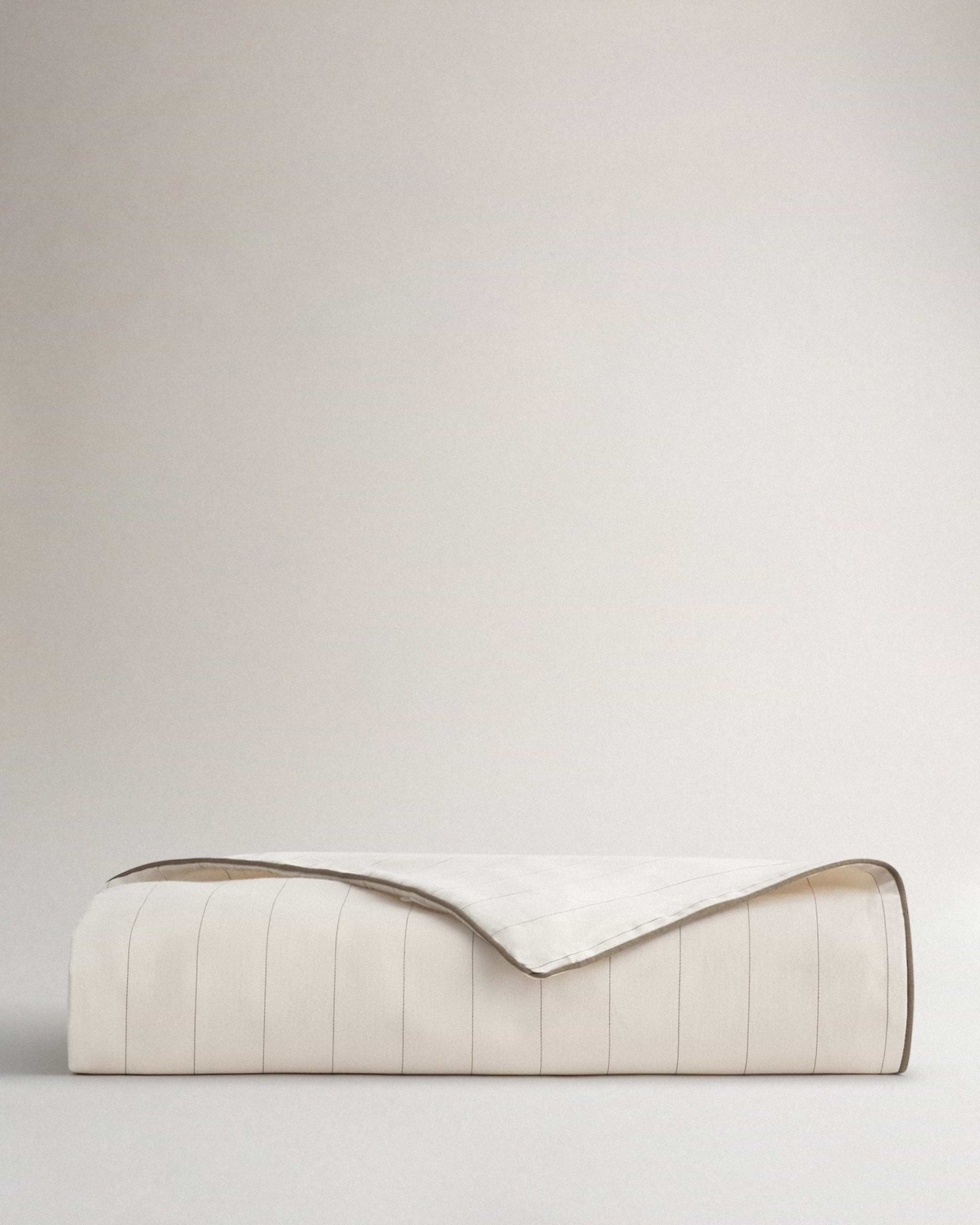 Image 1 of 2 showing Rise & Fall's sateen cotton duvet cover in buttermilk stripe.