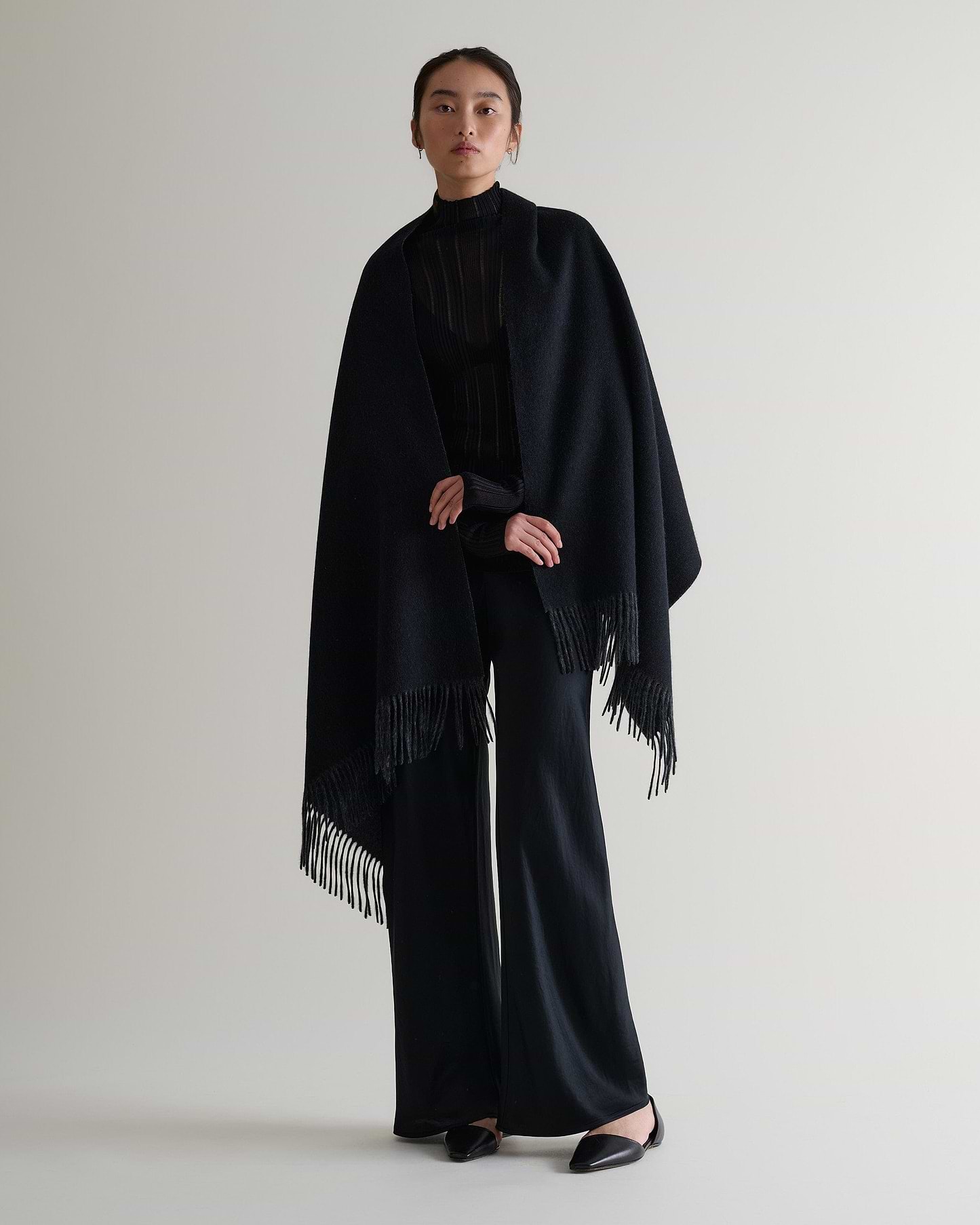 Image 1 of 5 showing woman wearing Rise & Fall's finest cashmere double faced wrap, colour: charcoal and black.