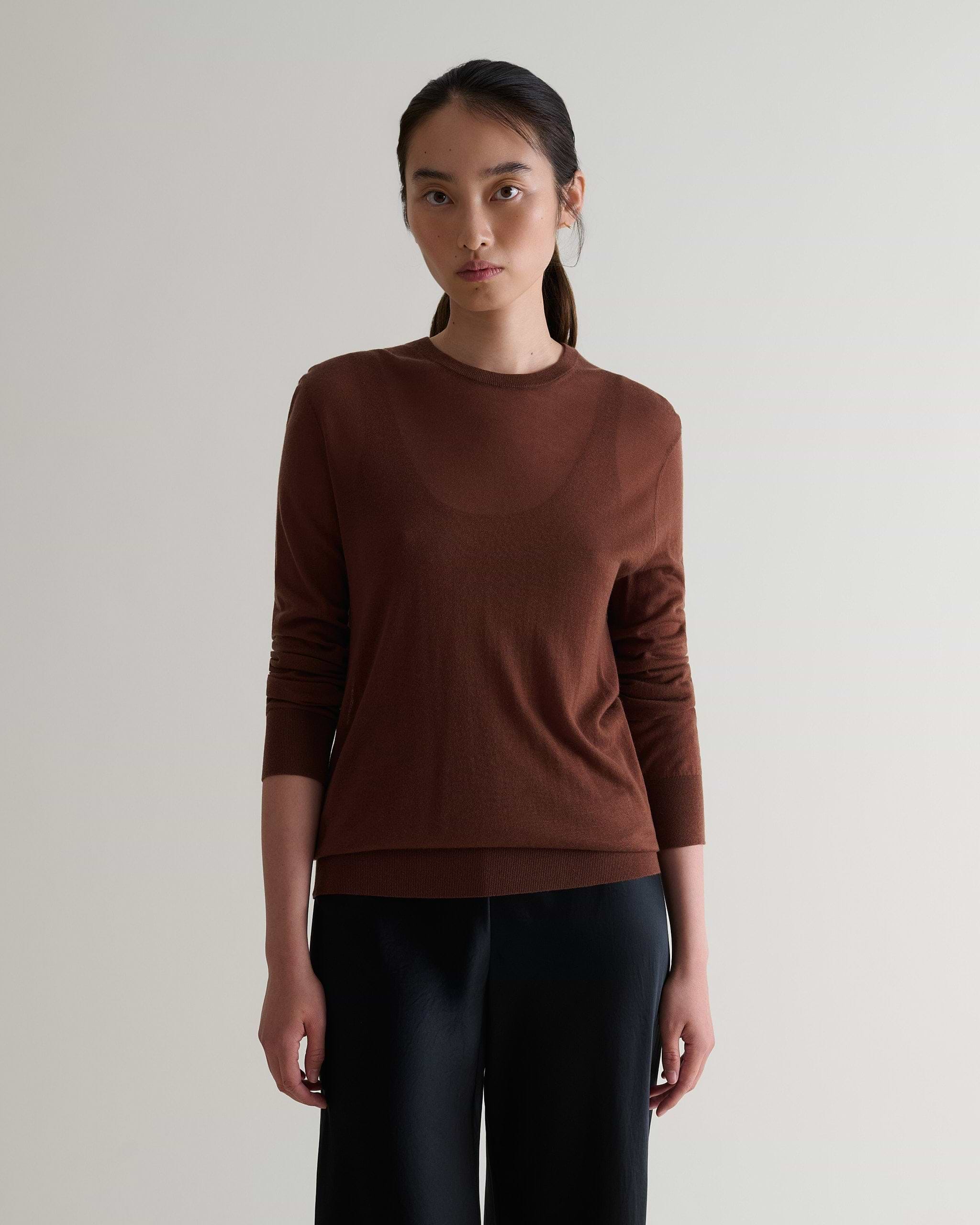 Image 1 of 6 showing woman wearing Rise & Fall's brown tencel cashmere double layered crew neck jumper with black trousers.