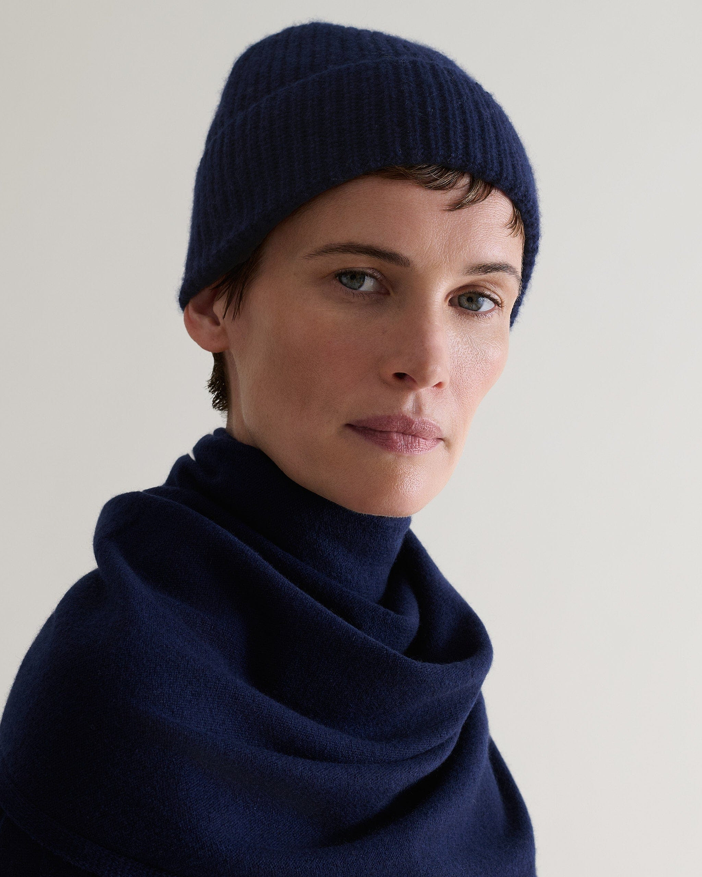 Image 3 of 3 showing close up of woman wearing Rise & Fall's Cashmere Merino Ribbed Knit Beanie in indigo blue.