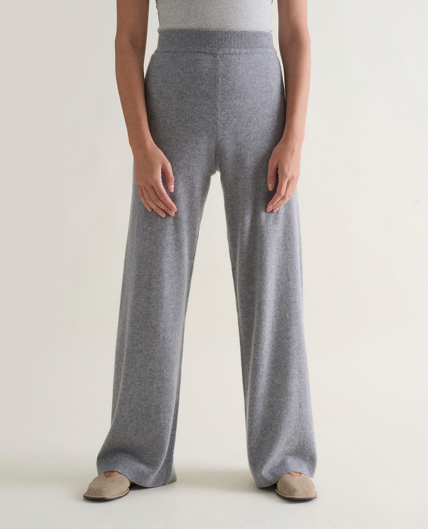 Image 3 of 3 showing woman wearing Rise & Fall's grey fine cashmere wide-leg trousers with white top.
