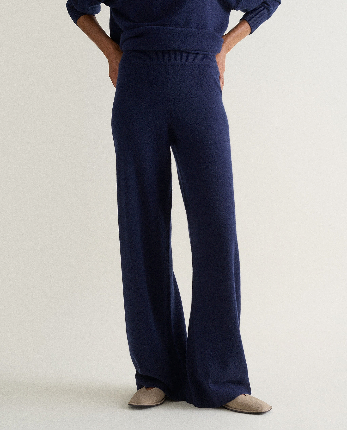 Image 3 of 3 showing woman wearing Rise & Fall's navy fine cashmere wide-leg trousers with matching cashmere sweatshirt.