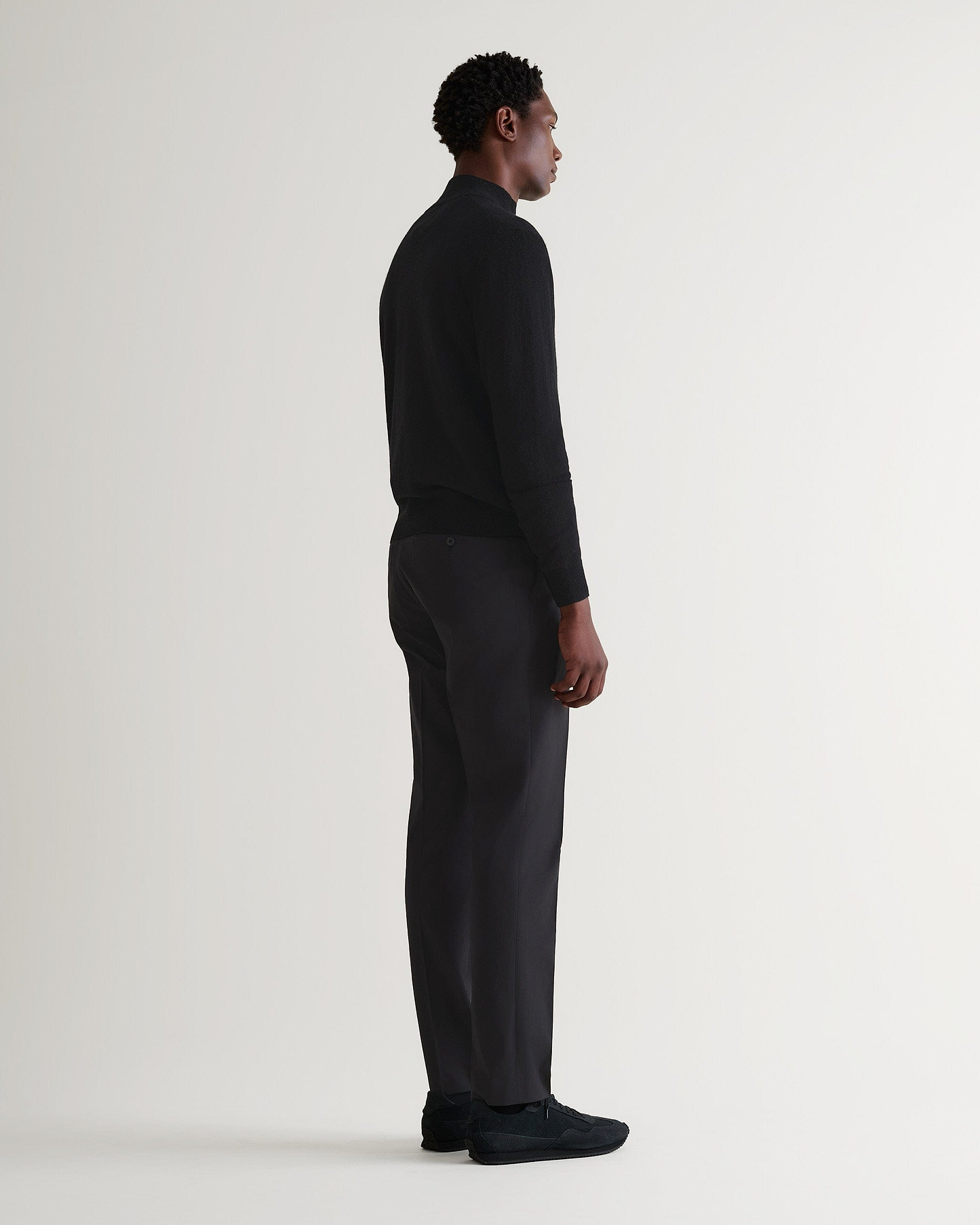 Image 3 of 5 showing man wearing Rise & Fall's fine cashmere 1/4 zip jumper, black.