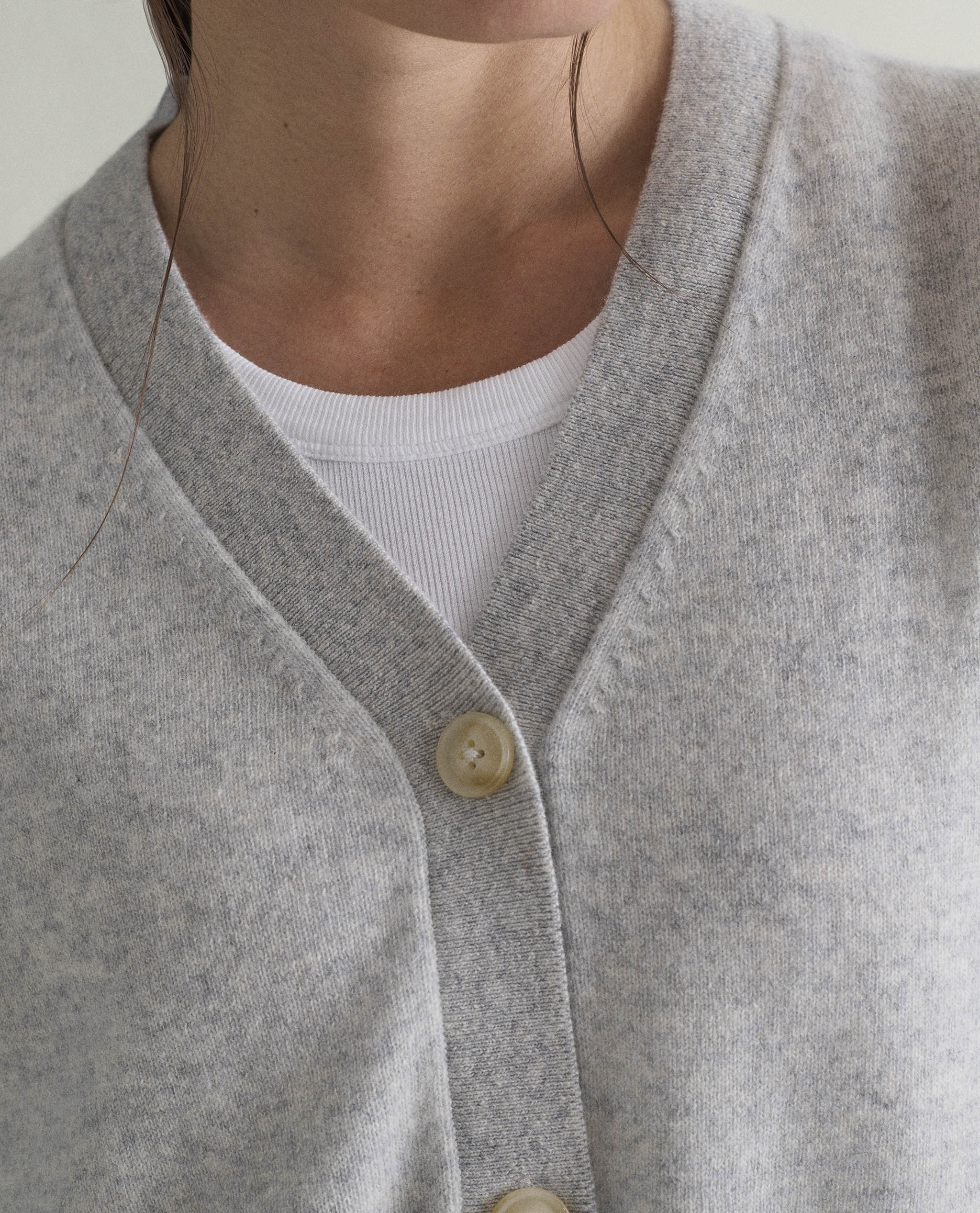 Image 3 of 5 showing close up of woman wearing Rise & Fall's grey fine cashmere v-neck cardigan.