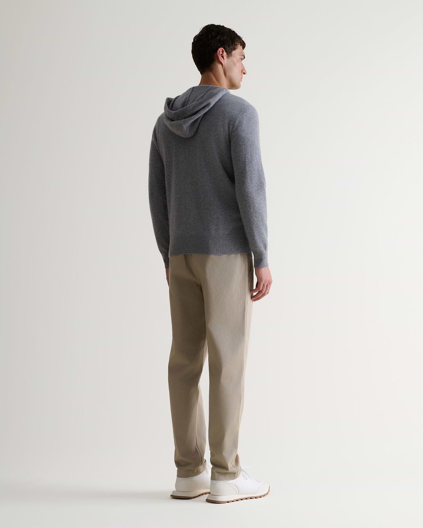 Image 3 of 6 showing man wearing Rise & Fall's fine cashmere zip hoodie, grey, back view.