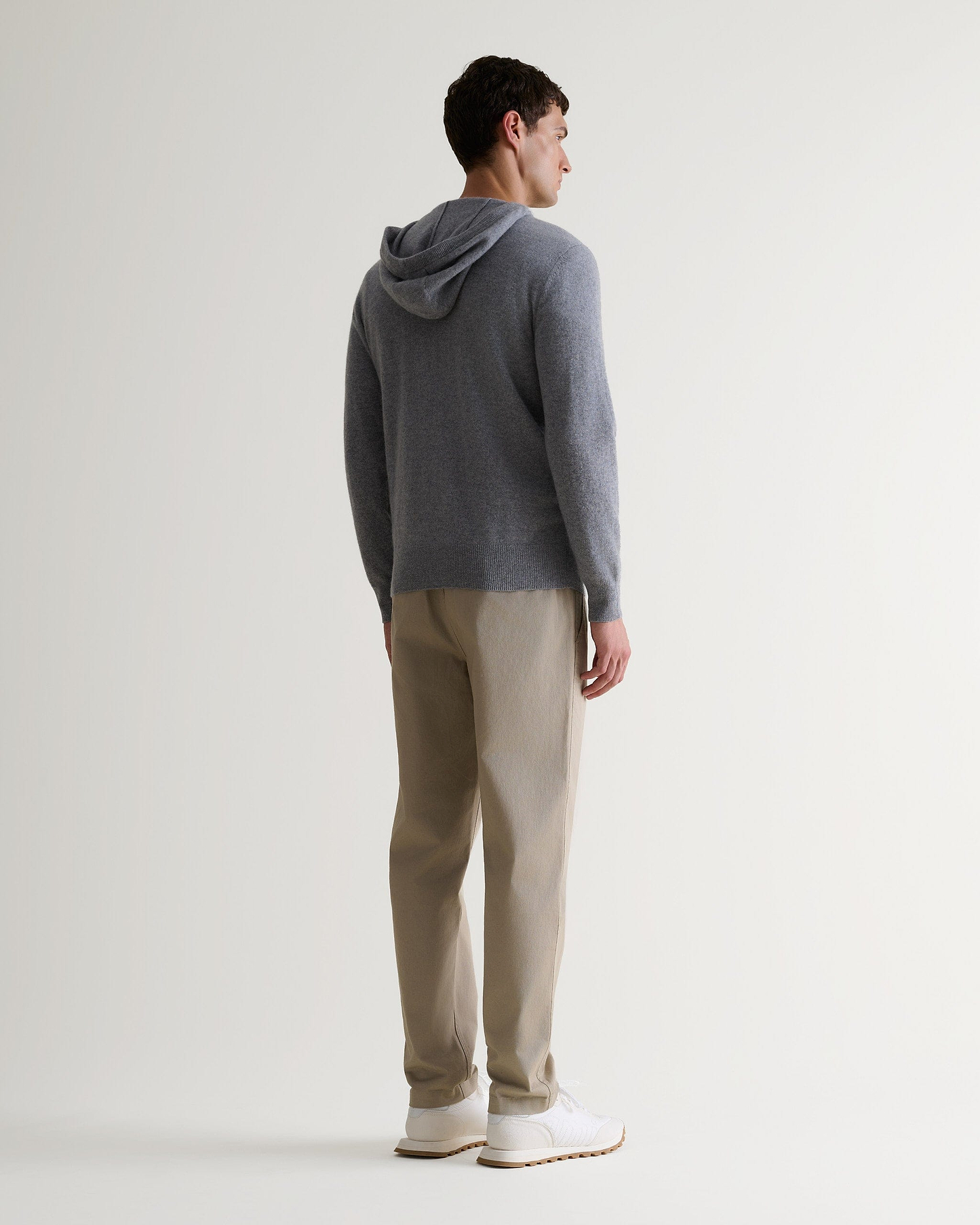Image 3 of 6 showing man wearing Rise & Fall's fine cashmere zip hoodie, grey, back view.