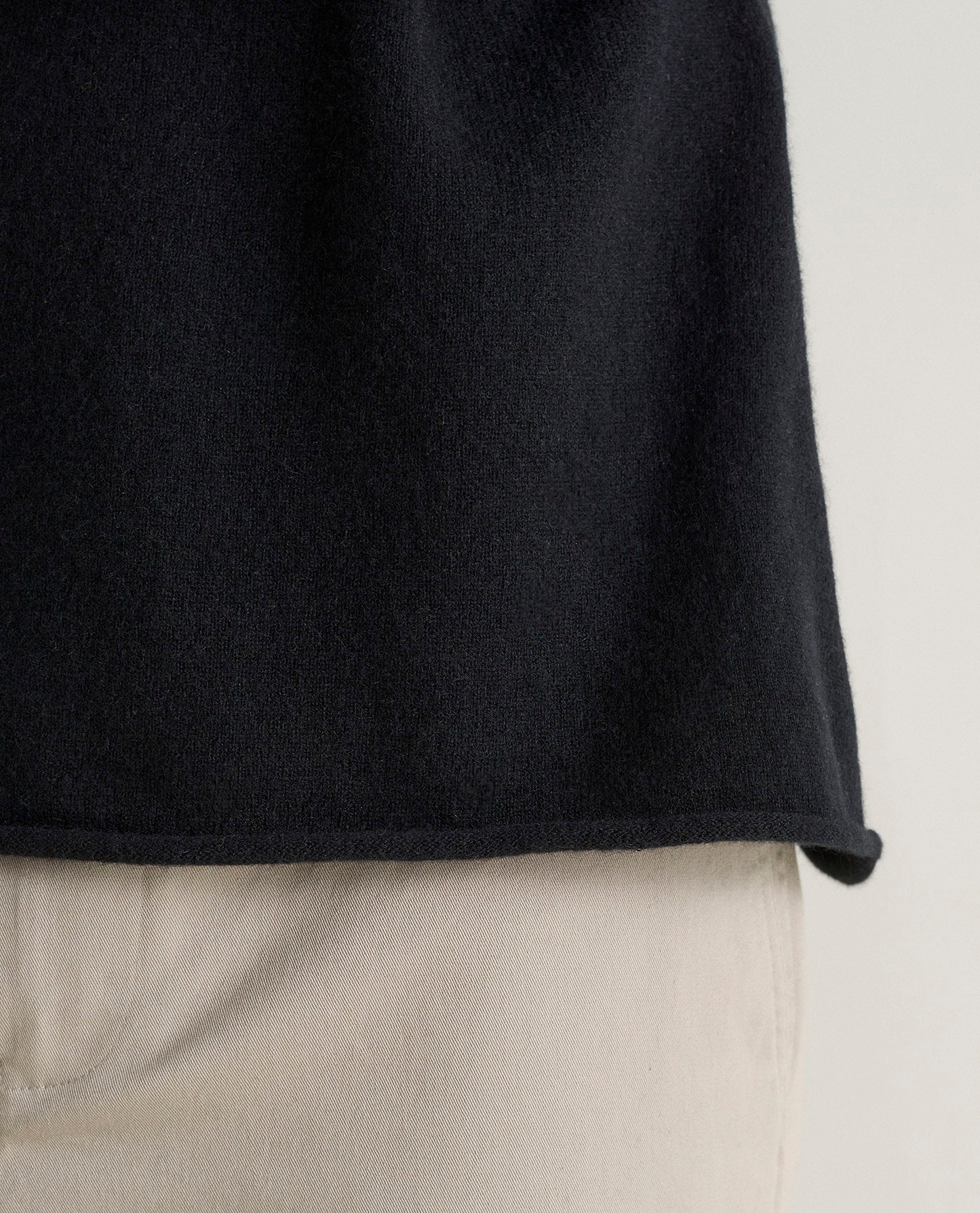 Image 5 of 5 showing close up of Rise & Fall's black finest cashmere sweatshirt with stone-coloured trousers.