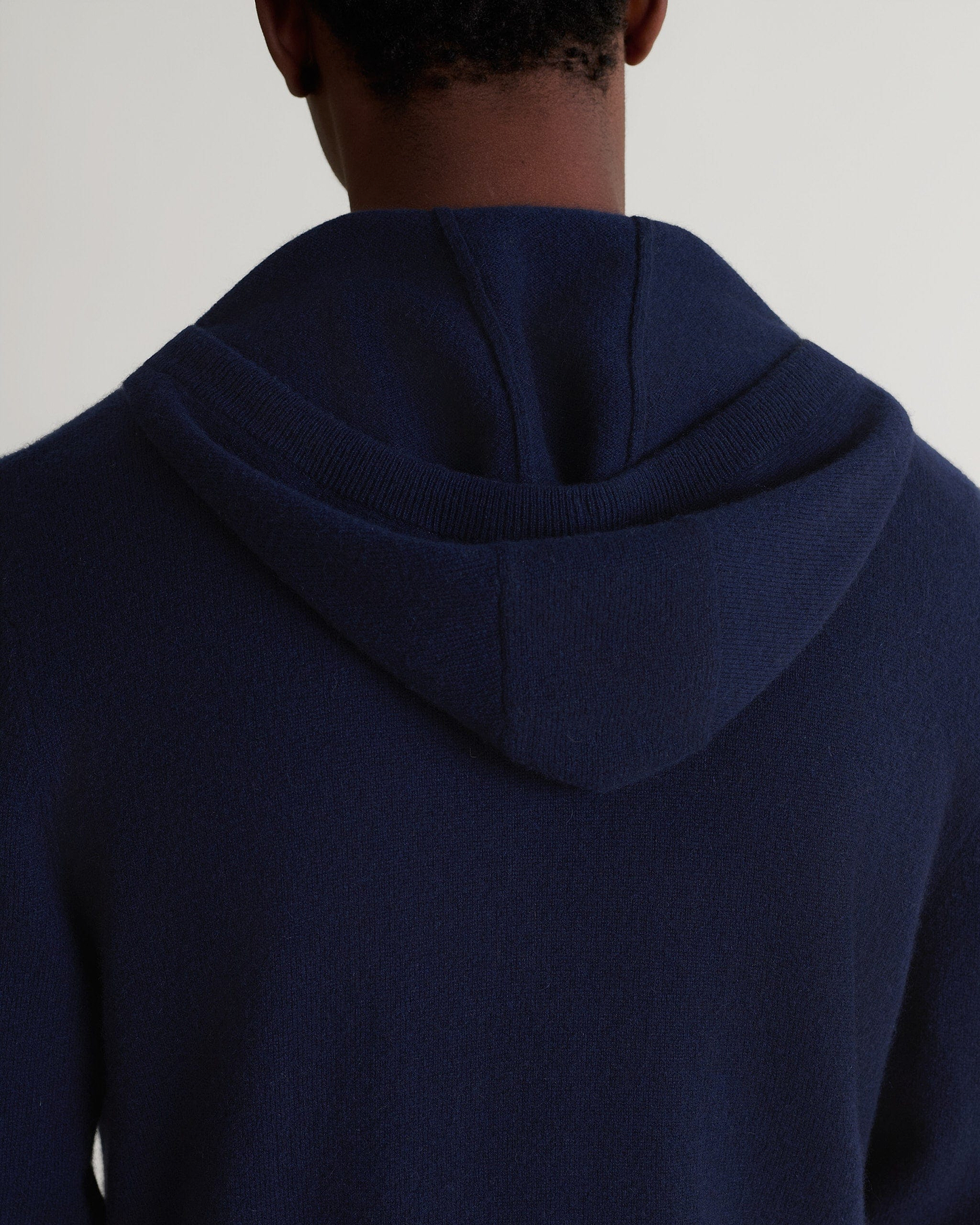 Image 5 of 5 showing man wearing Rise & Fall's fine cashmere zip hoodie, navy, close up.