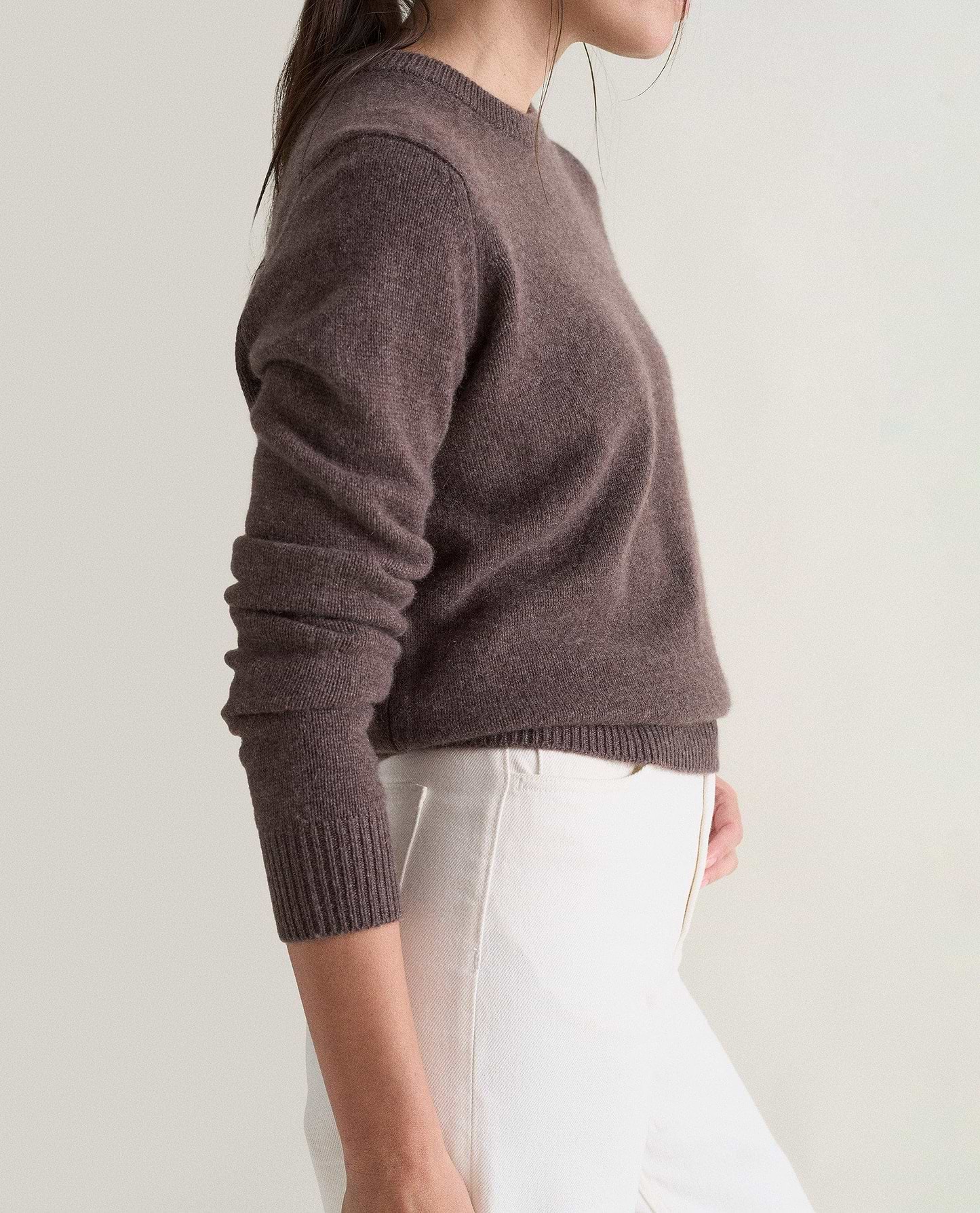 Image 5 of 5 showing the side of a woman wearing Rise & Fall's brown mid-weight cashmere crew neck jumper with white jeans.