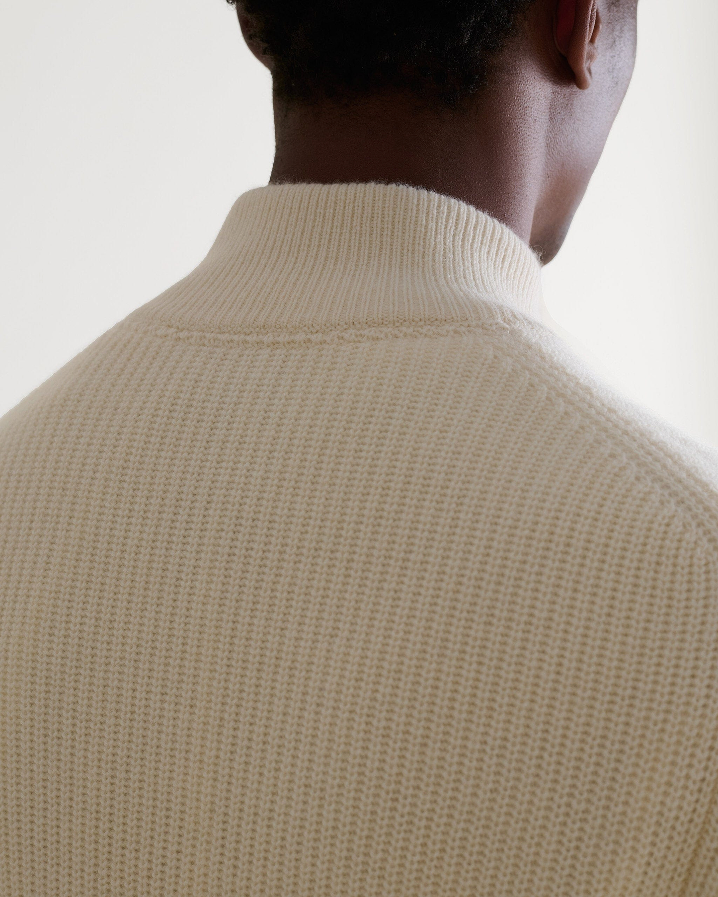 Image 5 of 6 showing close up man wearing Rise & Fall's Cashmere Merino Fishermans Rib 1/4 Zip Jumper in cream.
