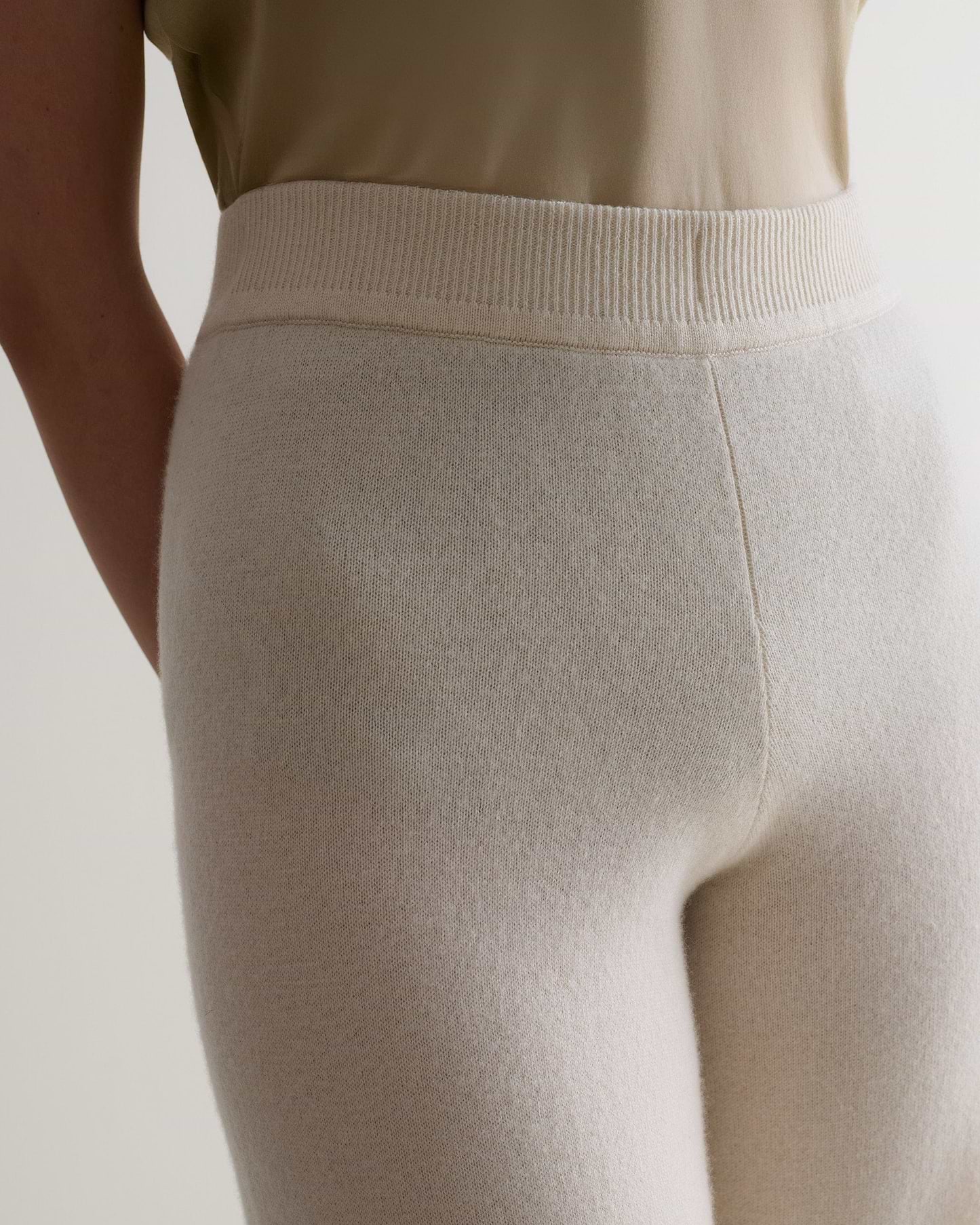 Image 5 of 6 showing close up of Rise & Fall's cream fine cashmere wide-leg trousers with beige t-shirt.