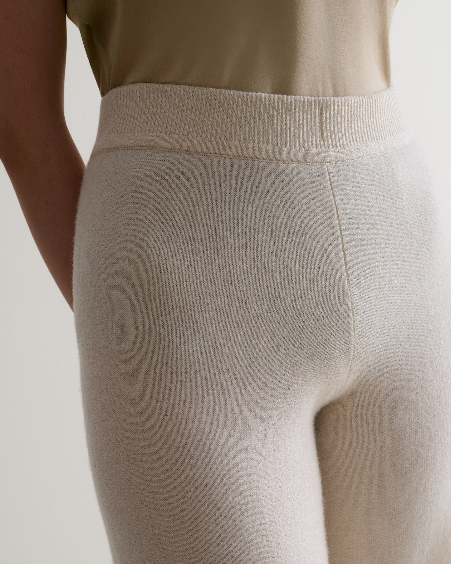 Image 5 of 6 showing close up of Rise & Fall's cream fine cashmere wide-leg trousers with beige t-shirt.