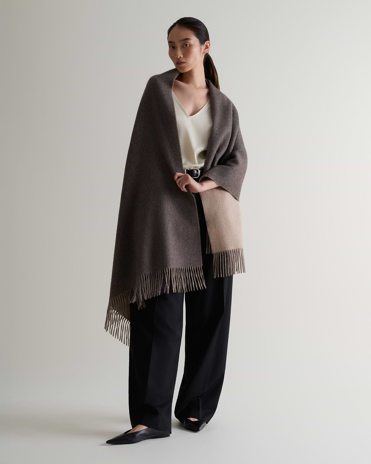 Image 5 of 7 showing woman wearing Rise & Fall's finest cashmere double faced wrap mole side with cream top and black trousers.