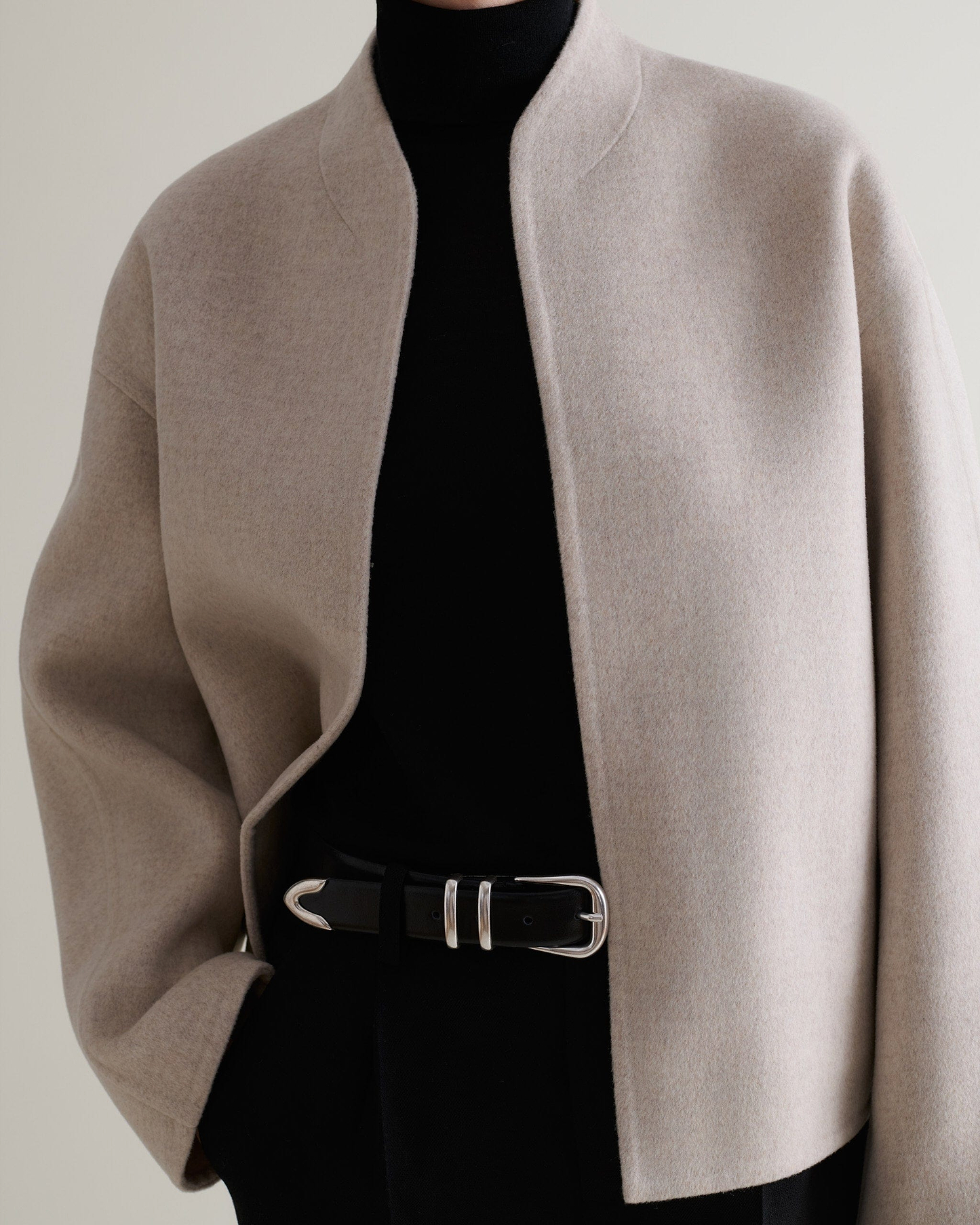 Image 5 of 9 showing Rise & Fall's twine cashmere wool double faced scarf jacket being worn with black roll neck, trousers and belt.