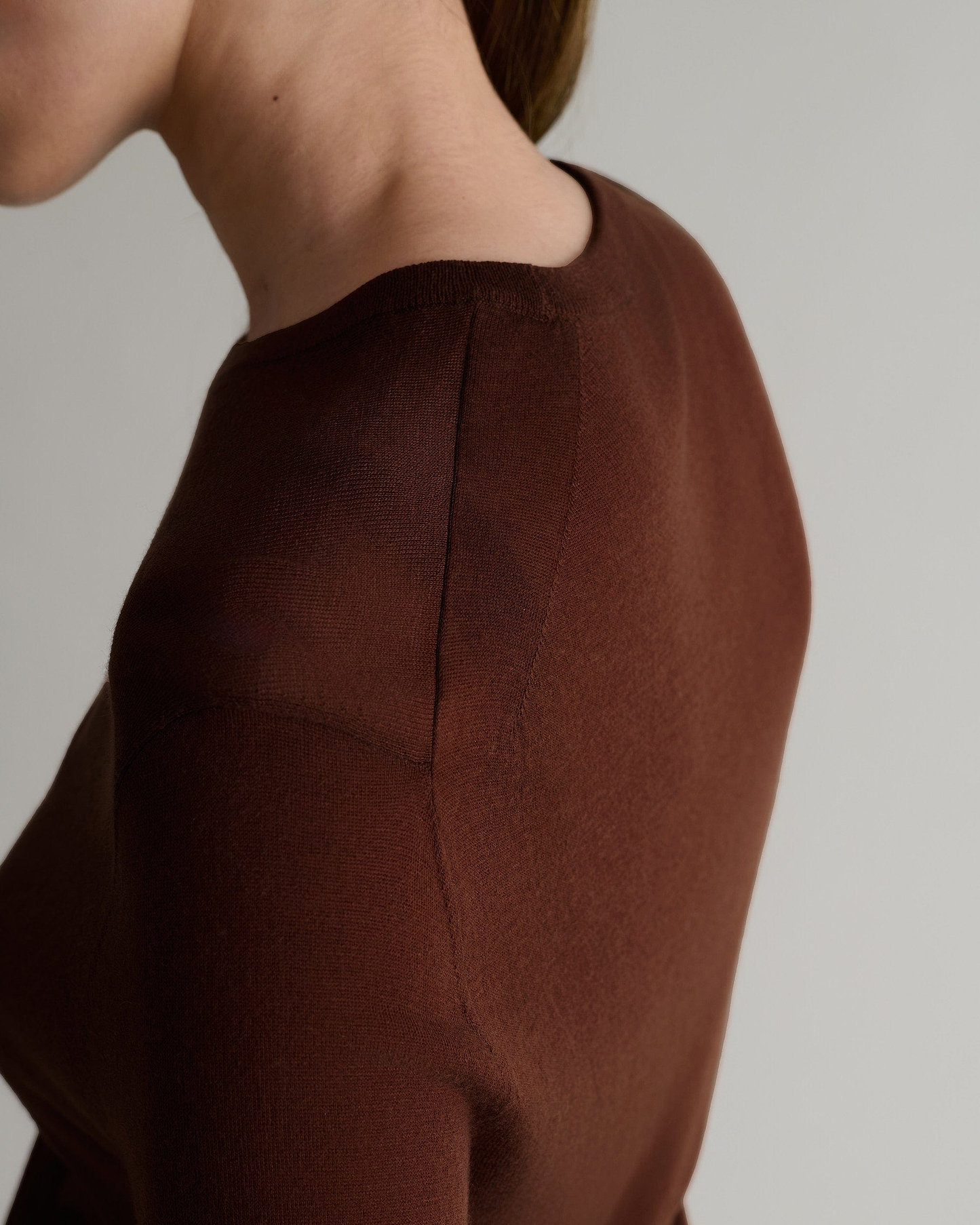 Image 6 of 6 showing close up of side view of woman wearing Rise & Fall's brown tencel cashmere double layered crew neck jumper. 
