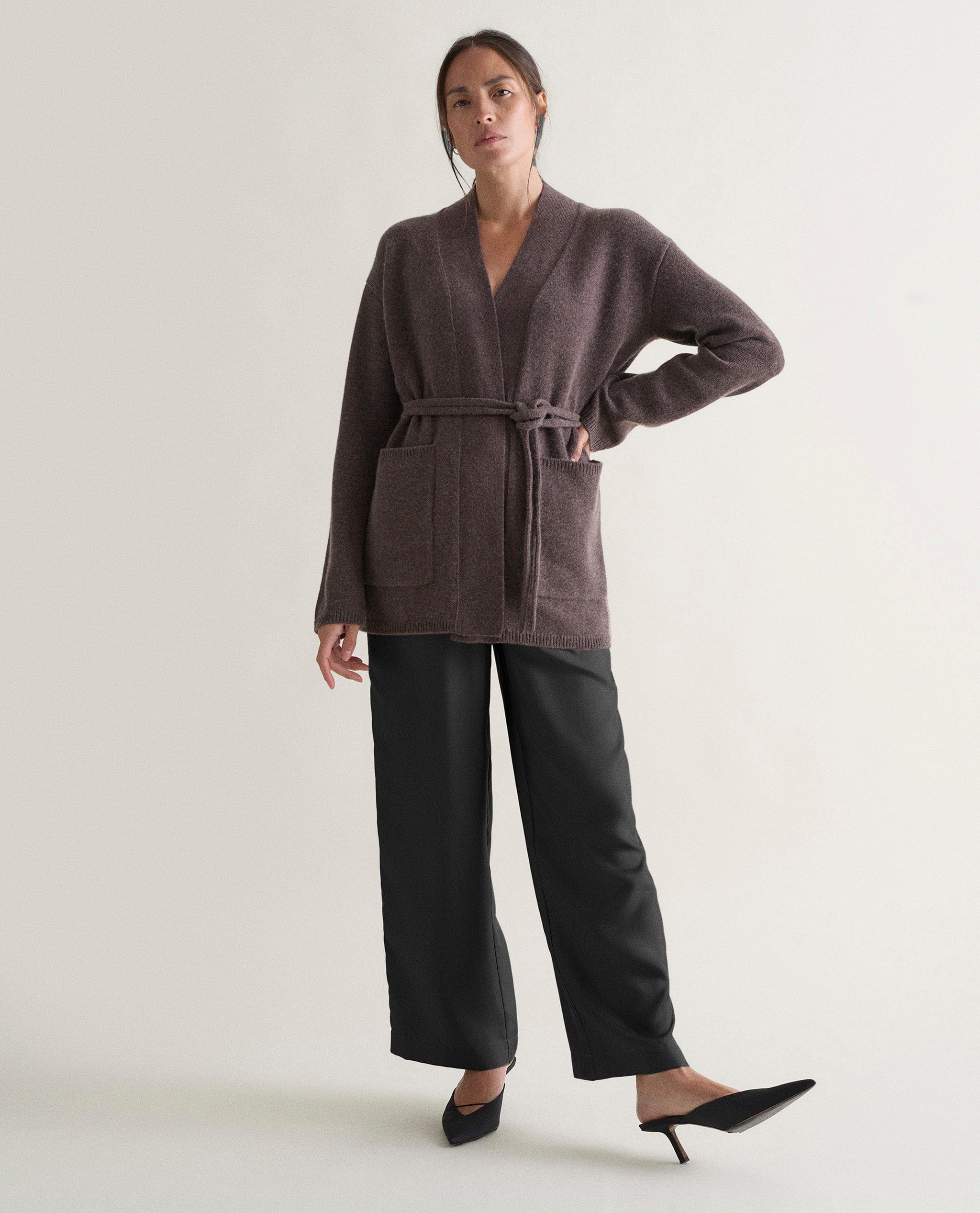 Image 6 of 6 showing woman wearing Rise & Fall's brown cashmere merino belted cardigan with silk brown trousers.