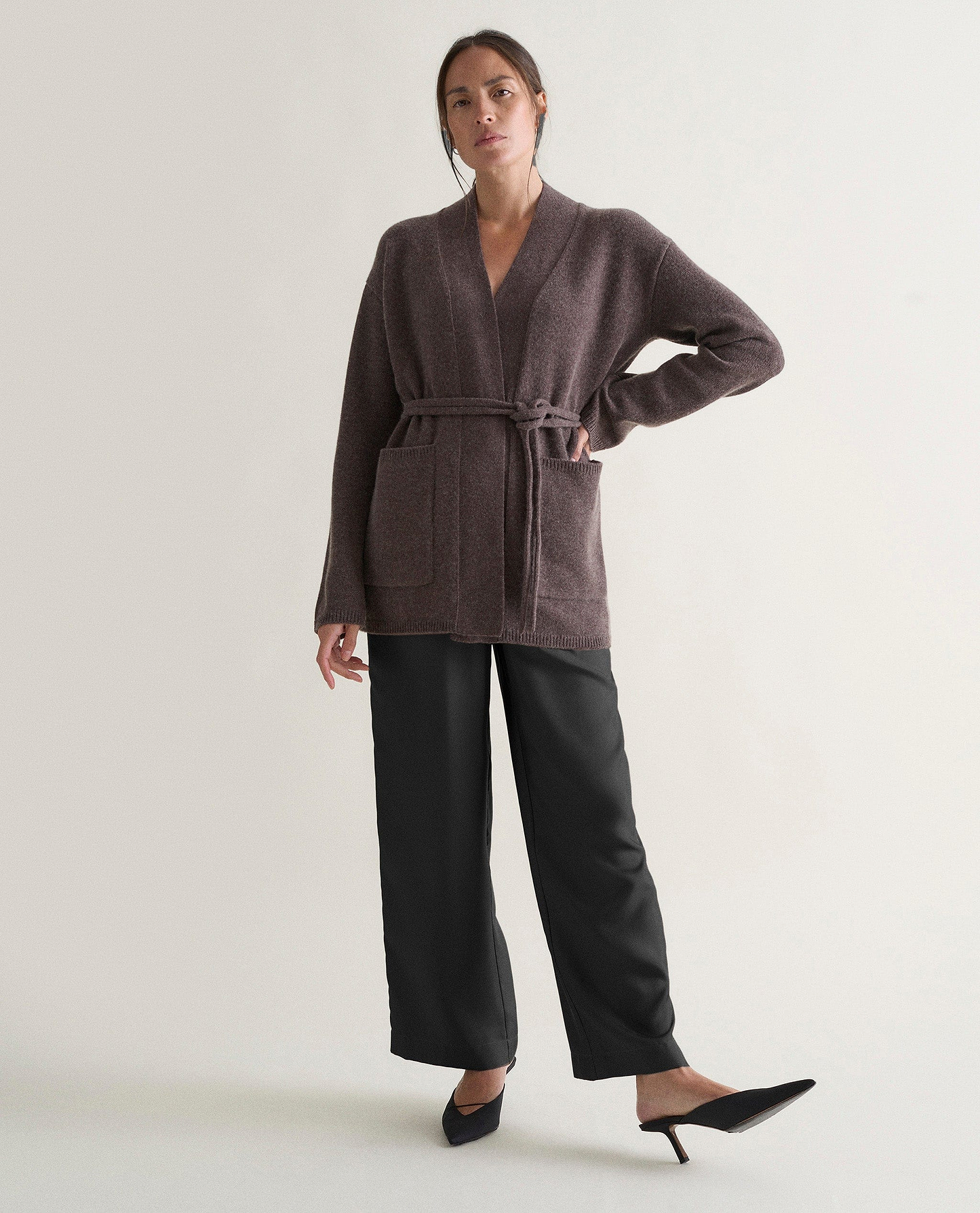 Image 6 of 6 showing woman wearing Rise & Fall's brown cashmere merino belted cardigan with silk brown trousers.