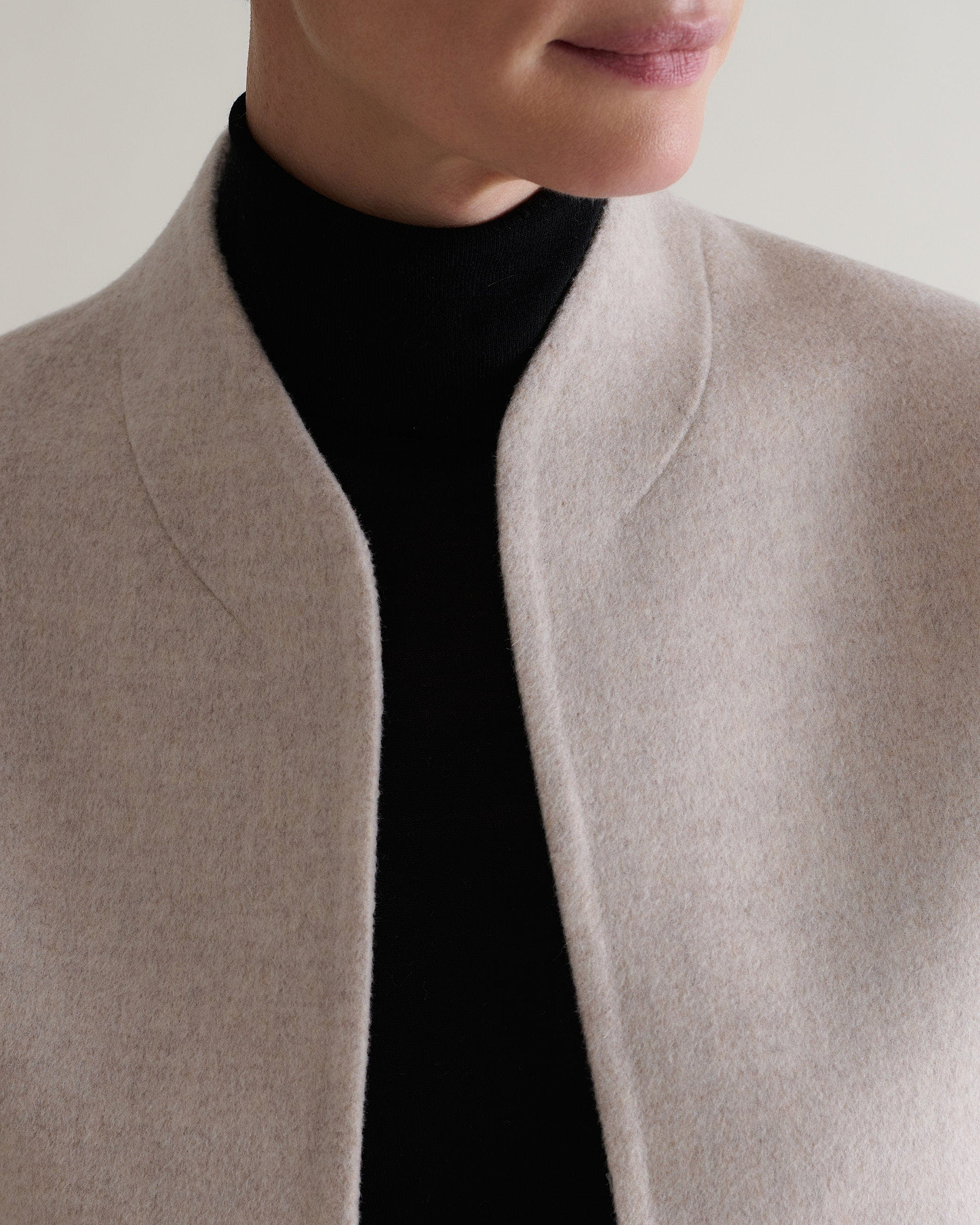 Image 6 of 9 showing close up of woman wearing Rise & Fall's twine cashmere wool double faced scarf jacket with black roll neck jumper.