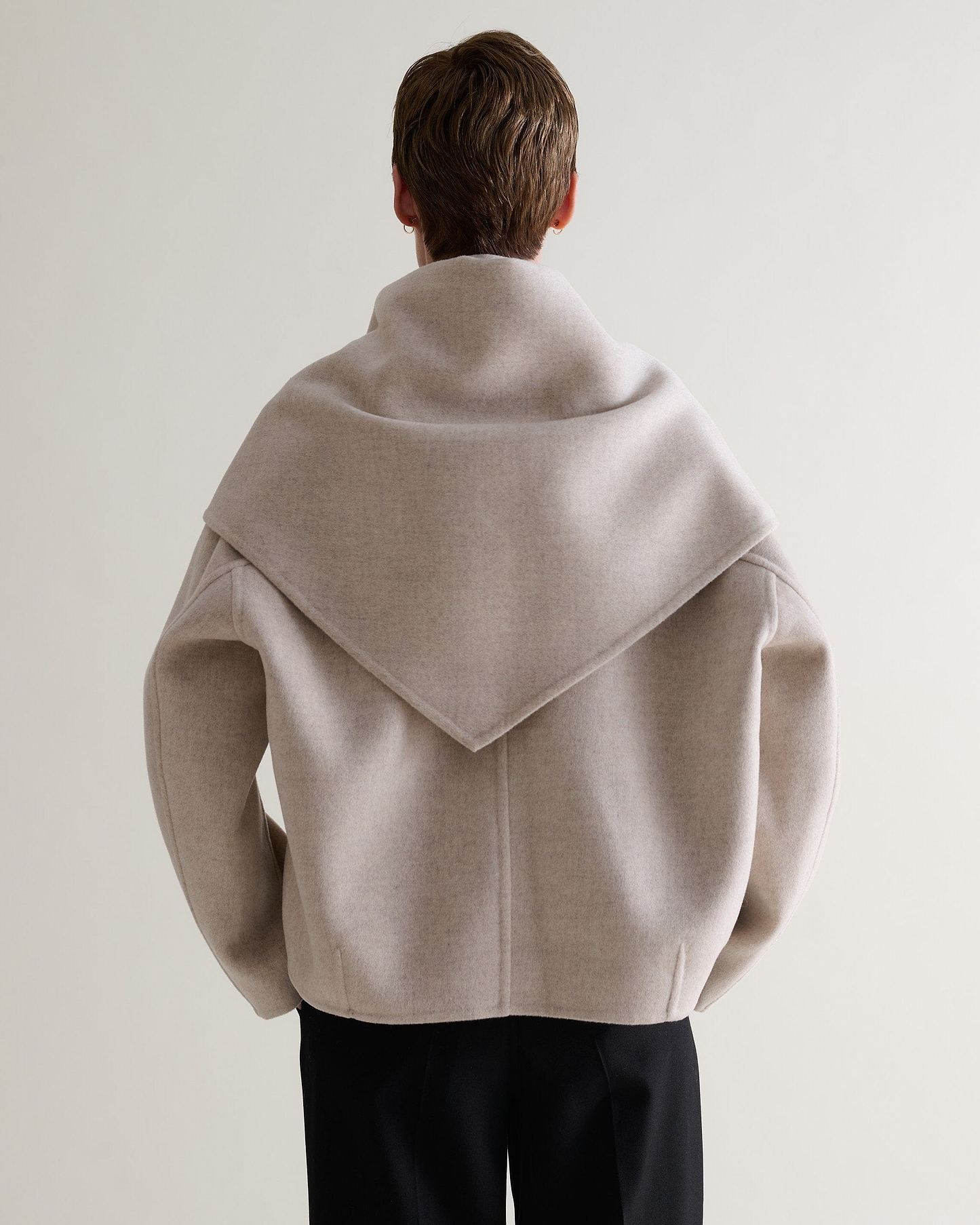 Image 9 of 9 showing back of woman wearing Rise & Fall's twine cashmere wool double faced scarf jacket with black trousers.