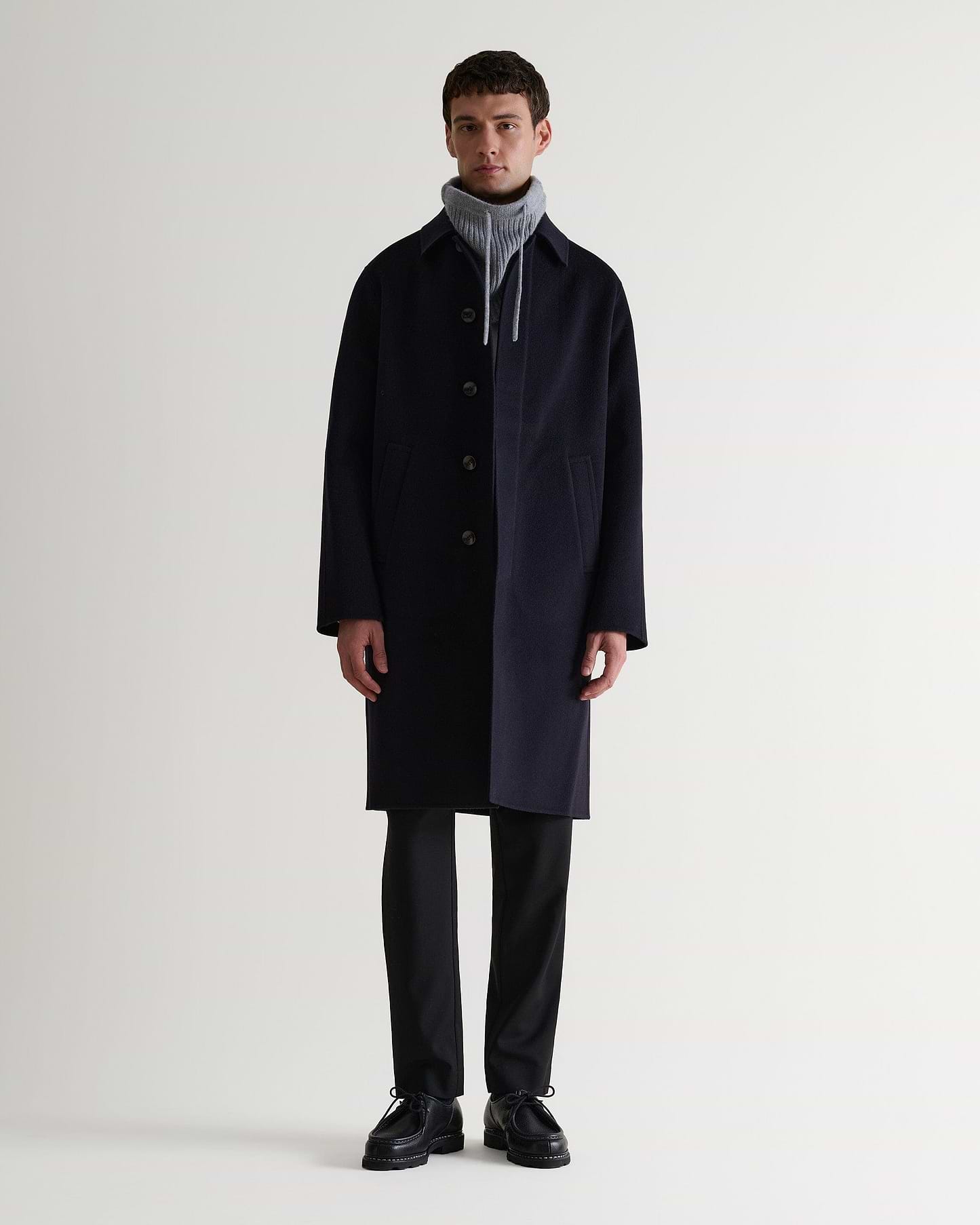 Full portrait of man wearing grey cashmere merino drawstring snood with navy wool coat