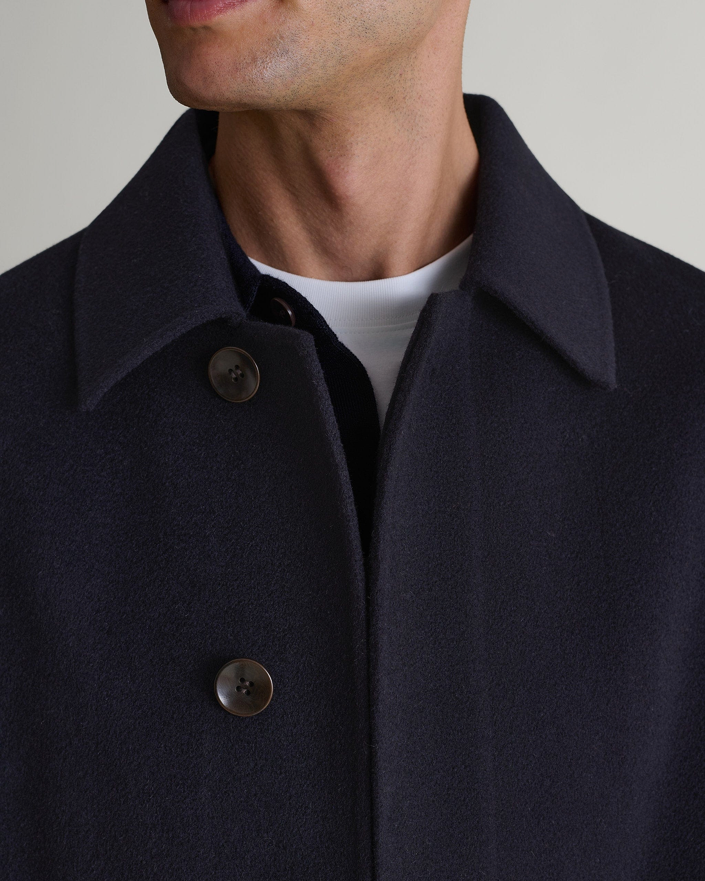 Man wears Rise & Fall's navy cashmere merino wool double-faced coat. Close up of front neckline.