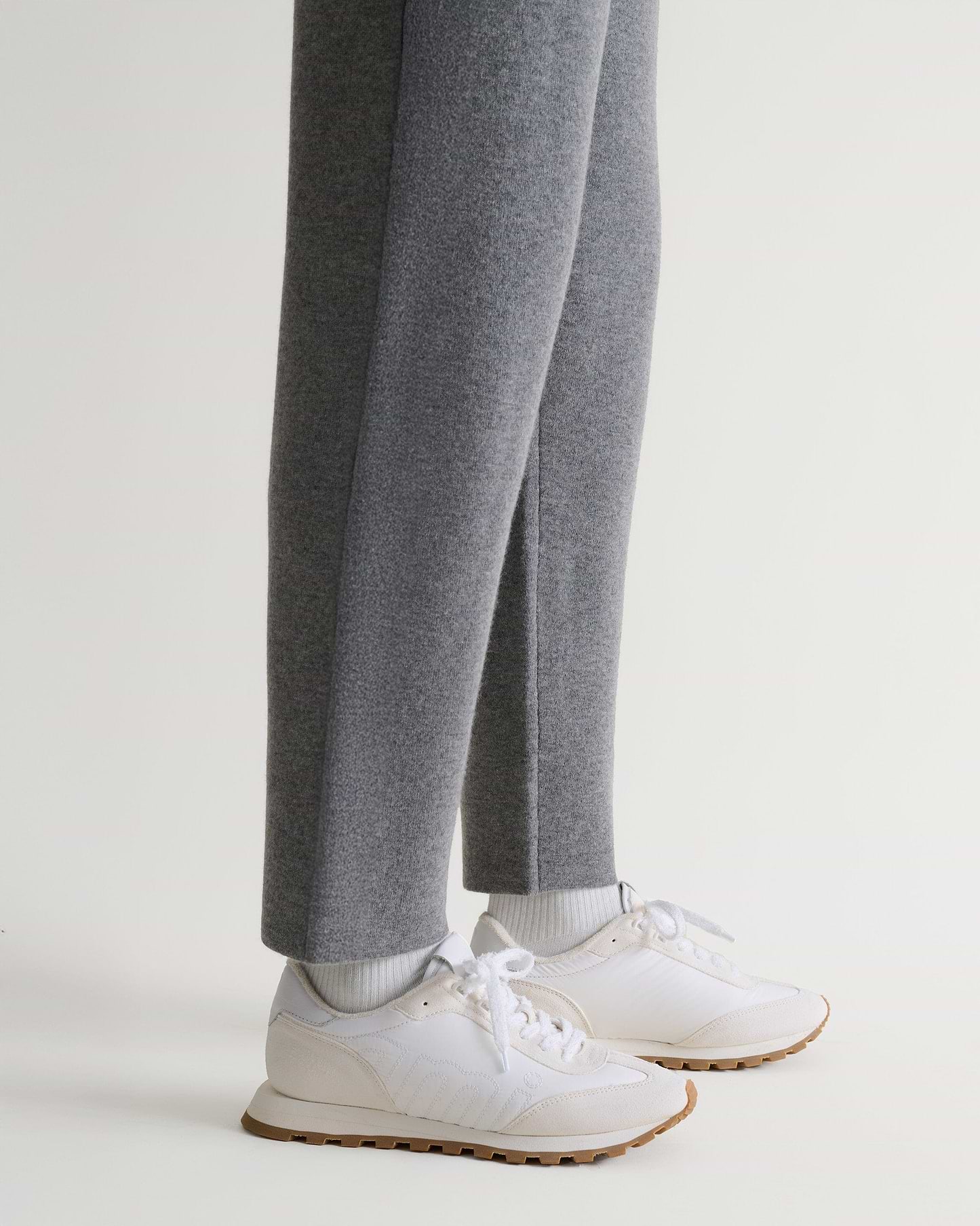Bottom side view of Rise & Fall's grey cashmere merino double-faced joggers with white trainers.
