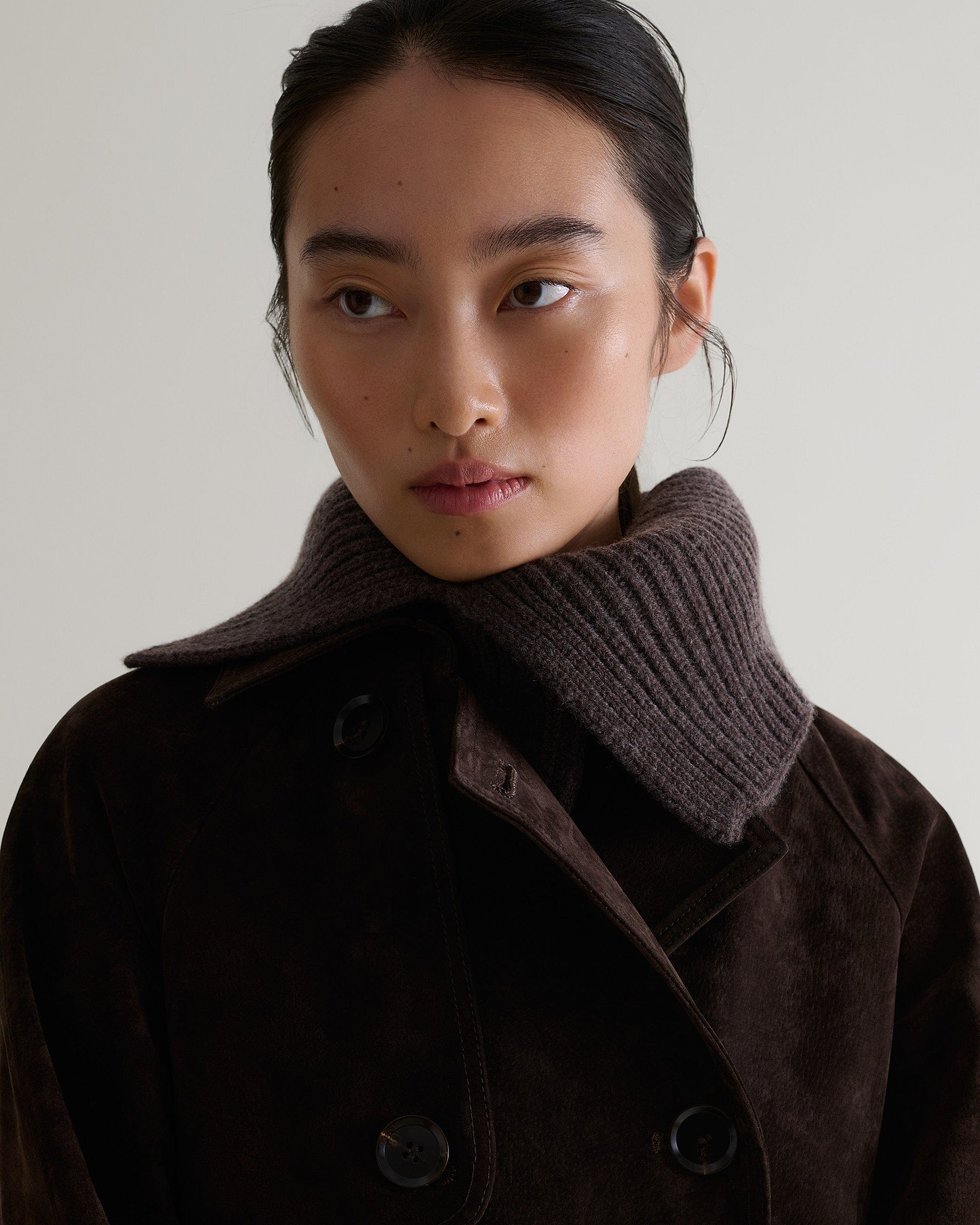 Close up of woman wearing Rise & Falls' brown cashmere merino ribbed collar. Worn with chocolate suede trench coat.