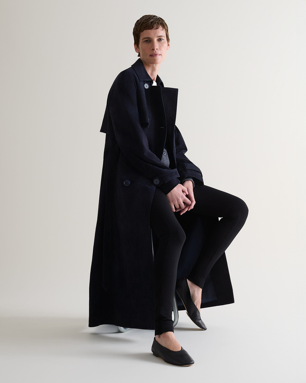 Woman wears Rise & Fall's navy suede coat.