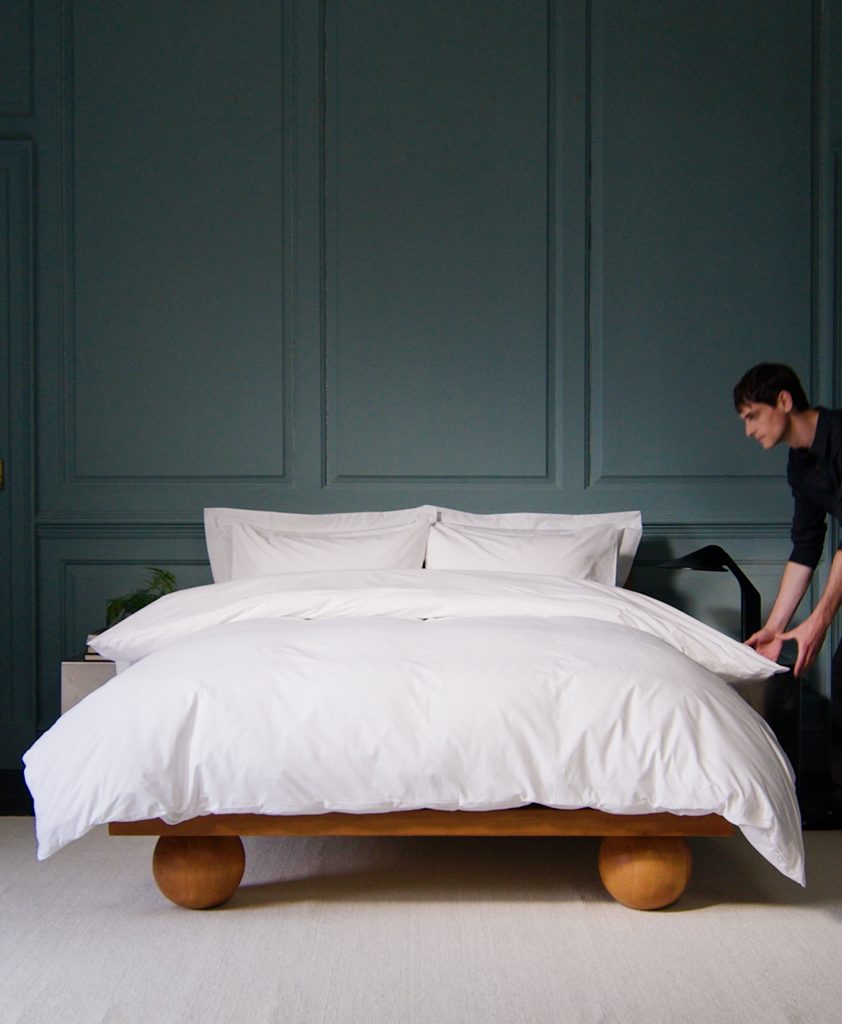 A man makes a bed with Rise & Fall's white cotton duvet set.