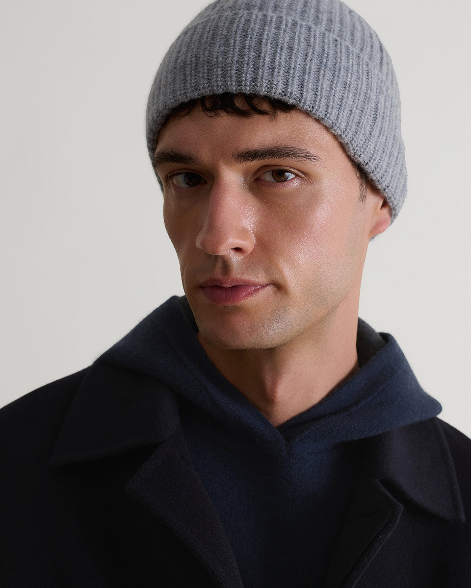 Close up of man wearing Rise & Fall's navy cashmere merino double-faced knitted hoodie with light grey beanie.