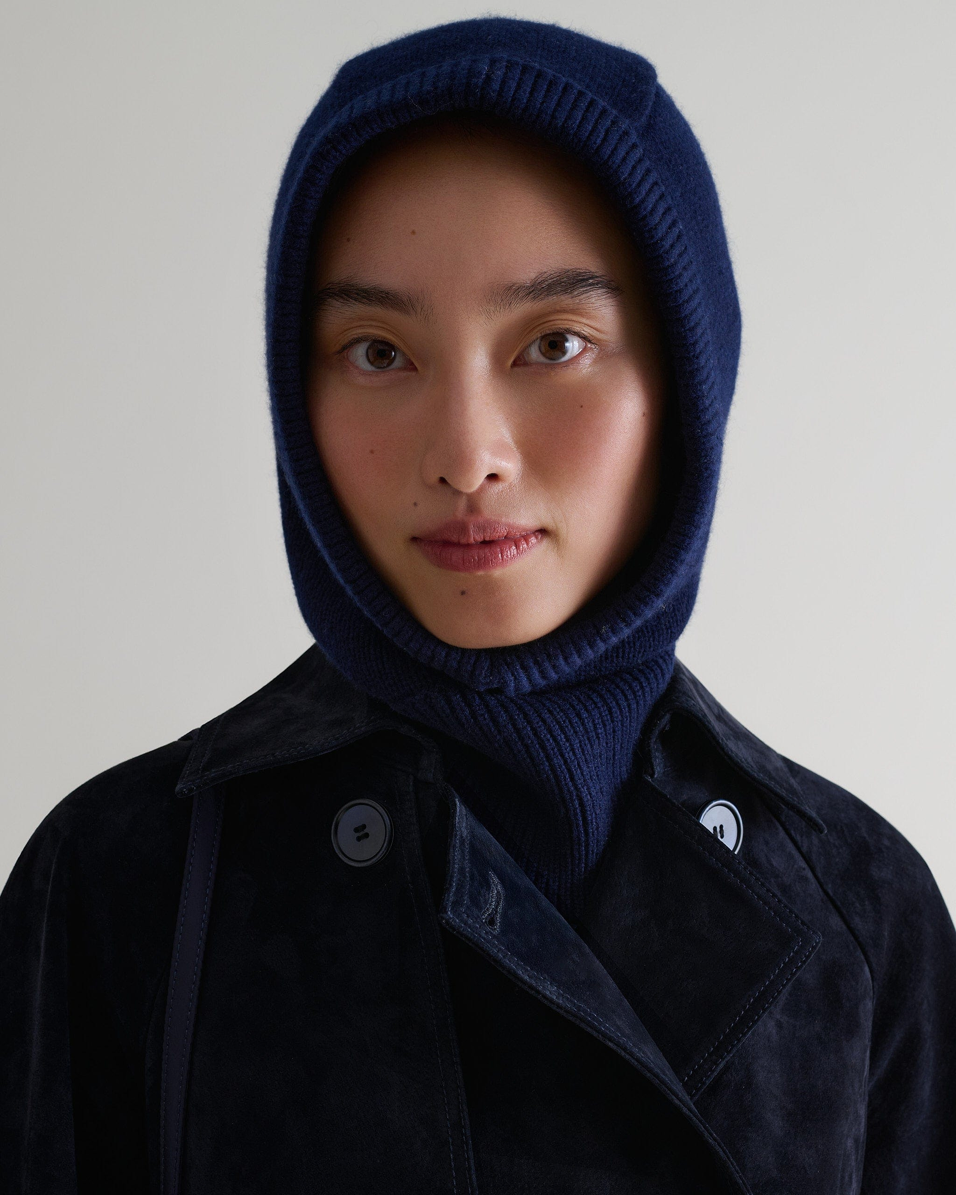 Image 1 of 3 showing woman wearing Rise & Fall's navy Cashmere Merino Knitted Hood.