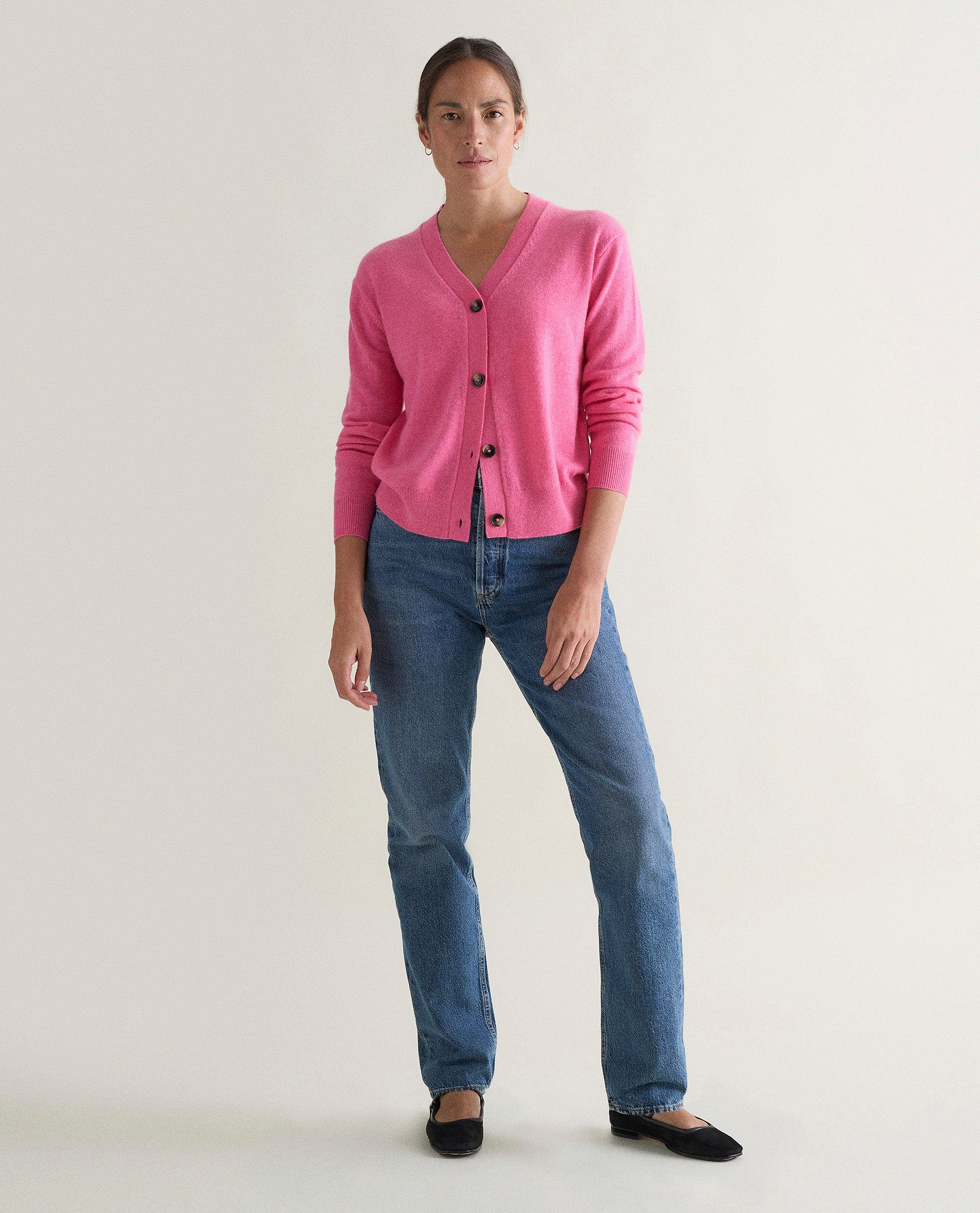 Image 1 of 3 showing woman wearing Rise & Fall's pink fine cashmere v-neck cardigan with jeans.