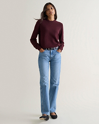 Image 1 of 3 showing woman wearing Rise & Fall's oxblood mid weight cashmere crew neck jumper with light blue jeans.