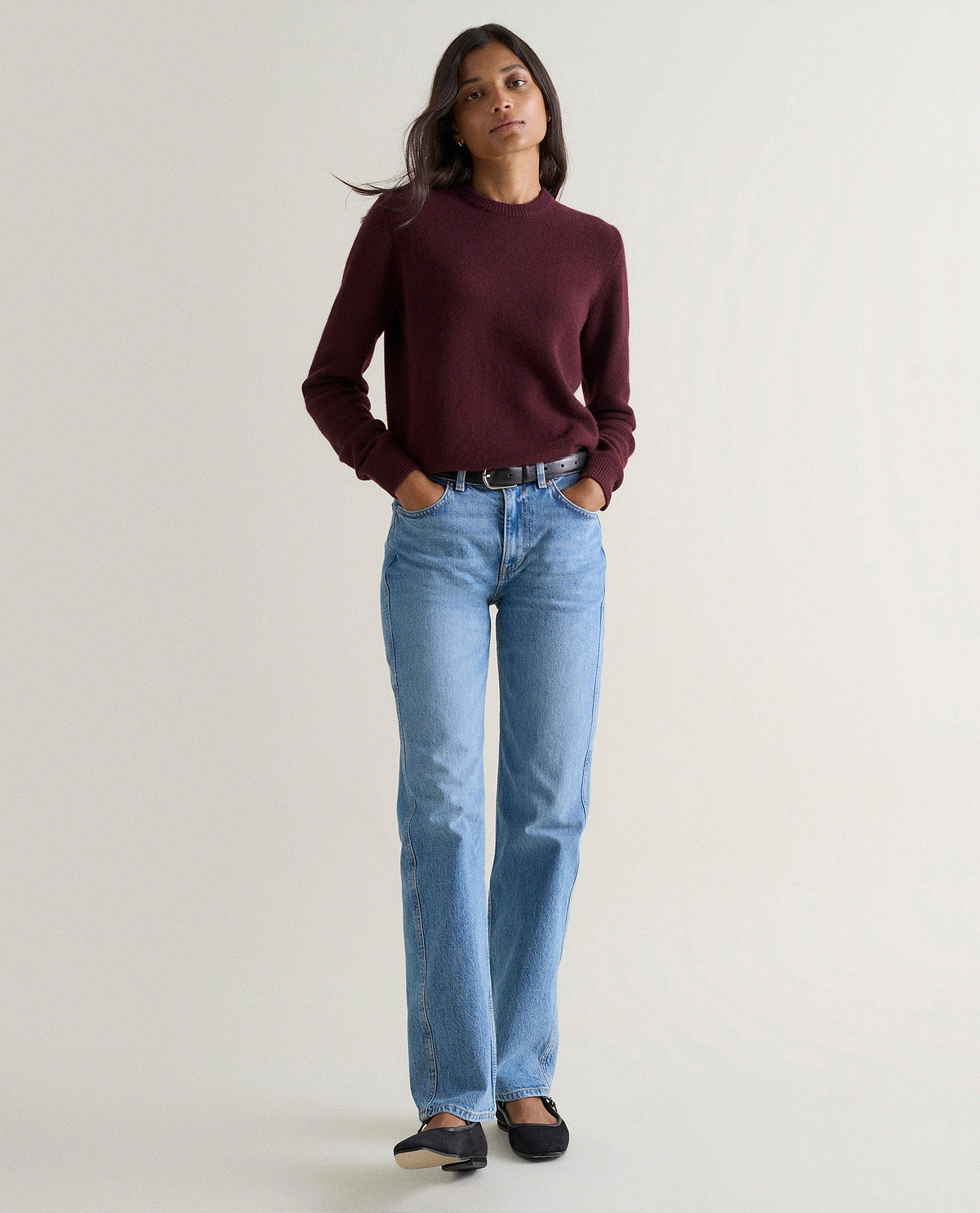 Image 1 of 3 showing woman wearing Rise & Fall's oxblood mid weight cashmere crew neck jumper with light blue jeans.