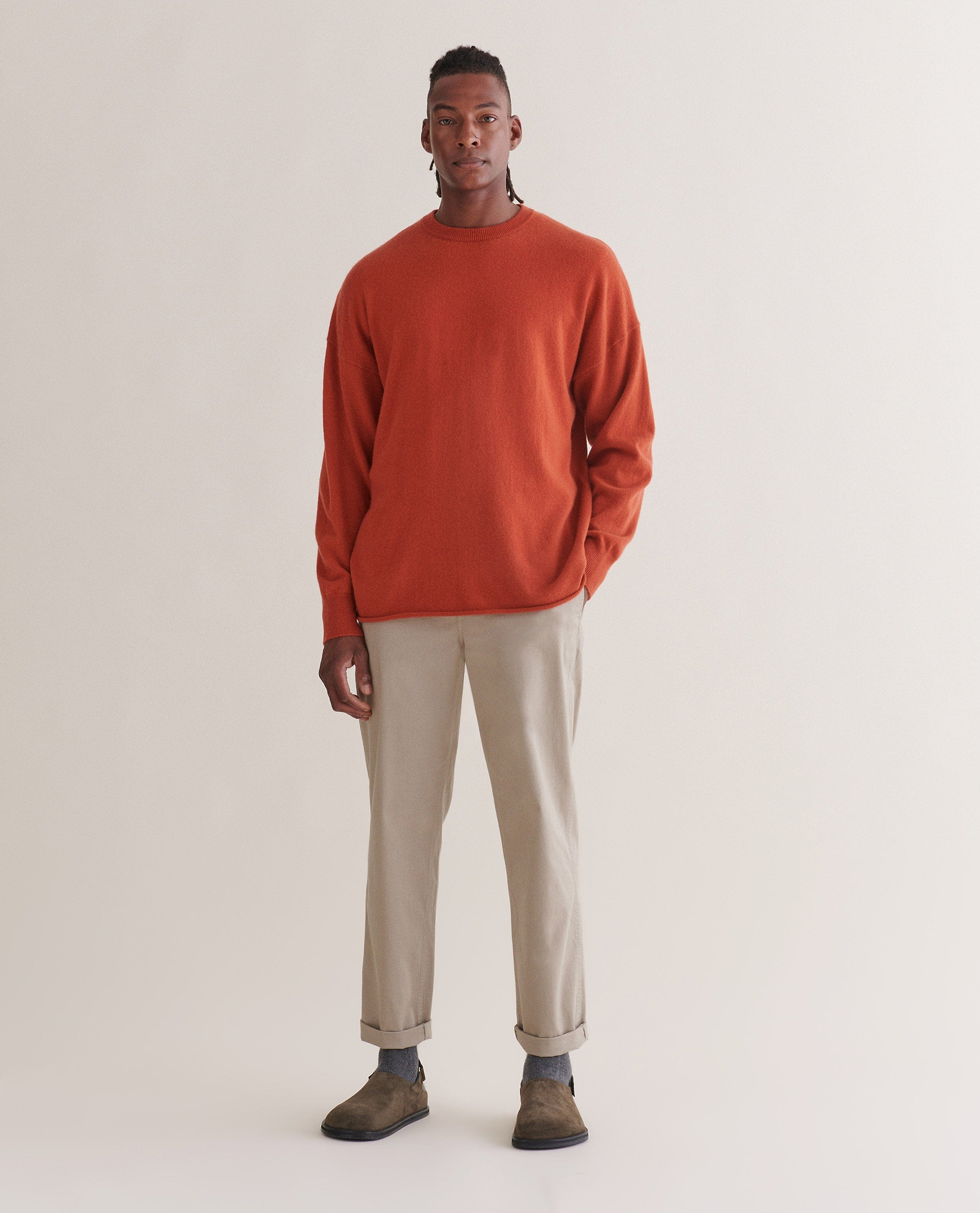 Image 1 of 4 showing man wearing Rise & Fall's finest cashmere sweatshirt in rust with stone-coloured trousers and brown suede shoes.