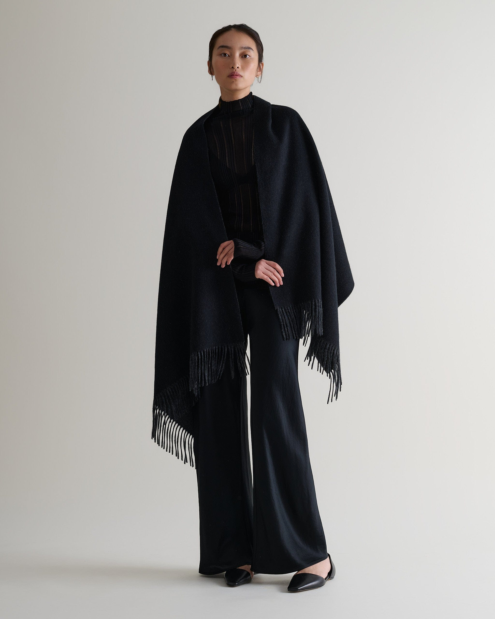Image 1 of 5 showing woman wearing Rise & Fall's finest cashmere double faced wrap, colour: charcoal and black.