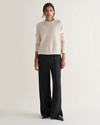 Image 1 of 5 showing woman wearing Rise & Fall's cream mid-weight cashmere crew neck jumper with black trousers.