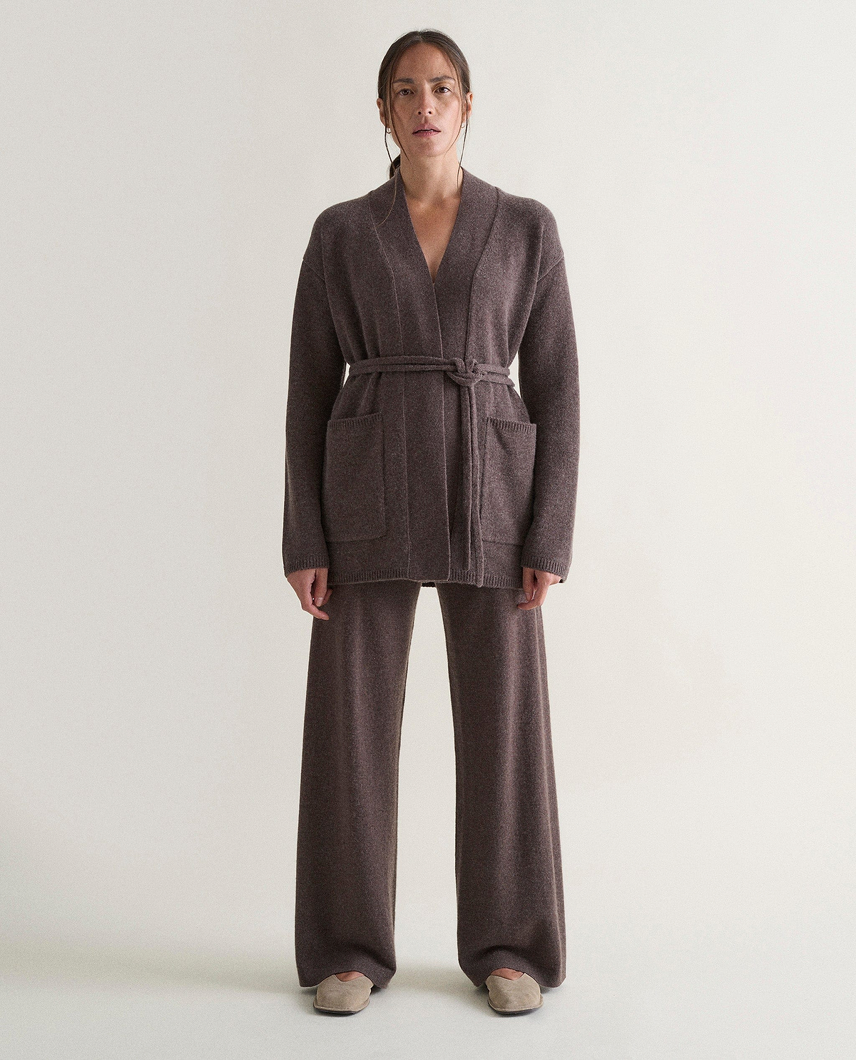 Image 1 of 6 showing woman wearing Rise & Fall's brown cashmere merino belted cardigan with matching cashmere trousers.