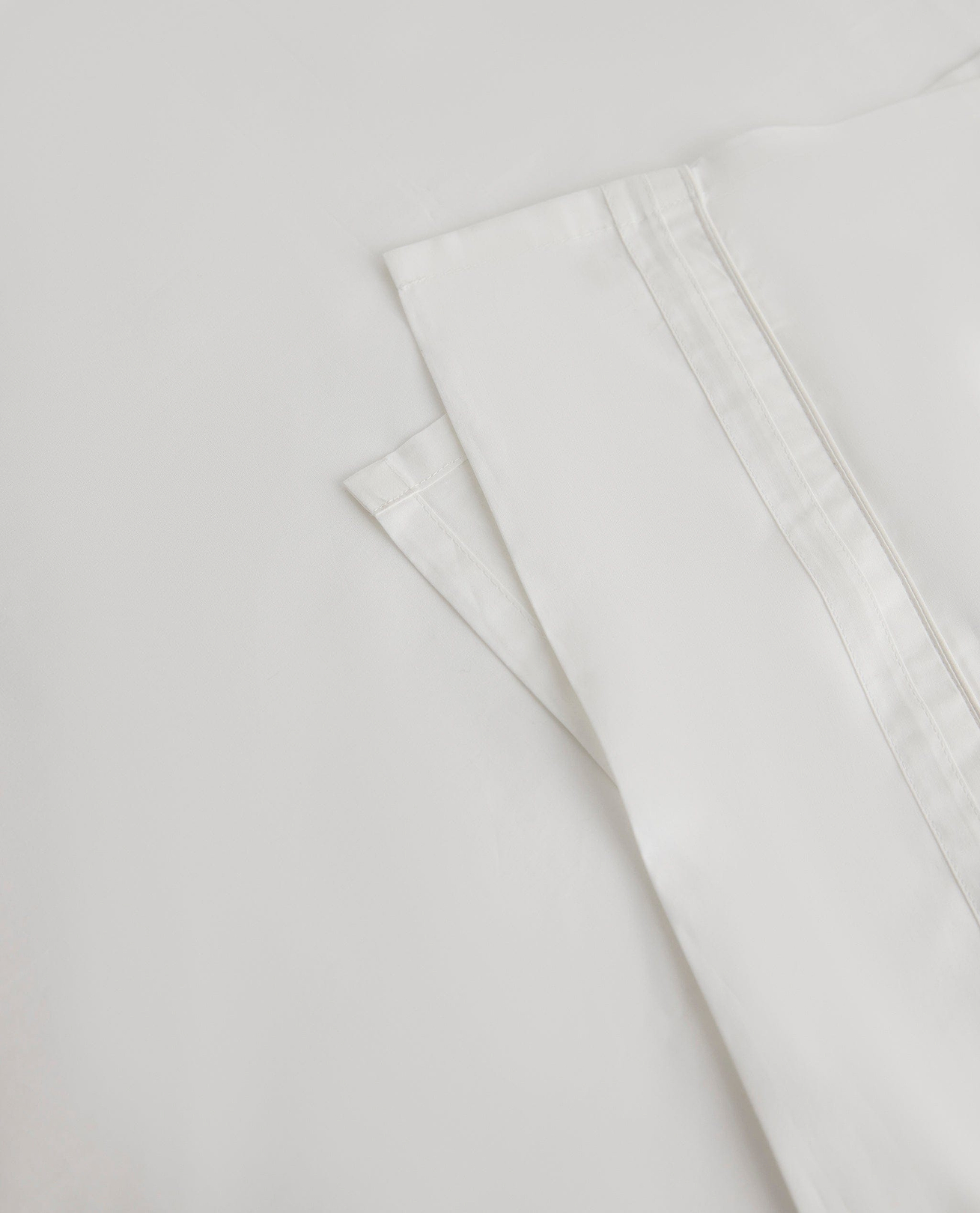 Image 2 of 5 showing Rise & Fall's Crisp & Cool organic percale cotton flat bed sheet in white tailored border.